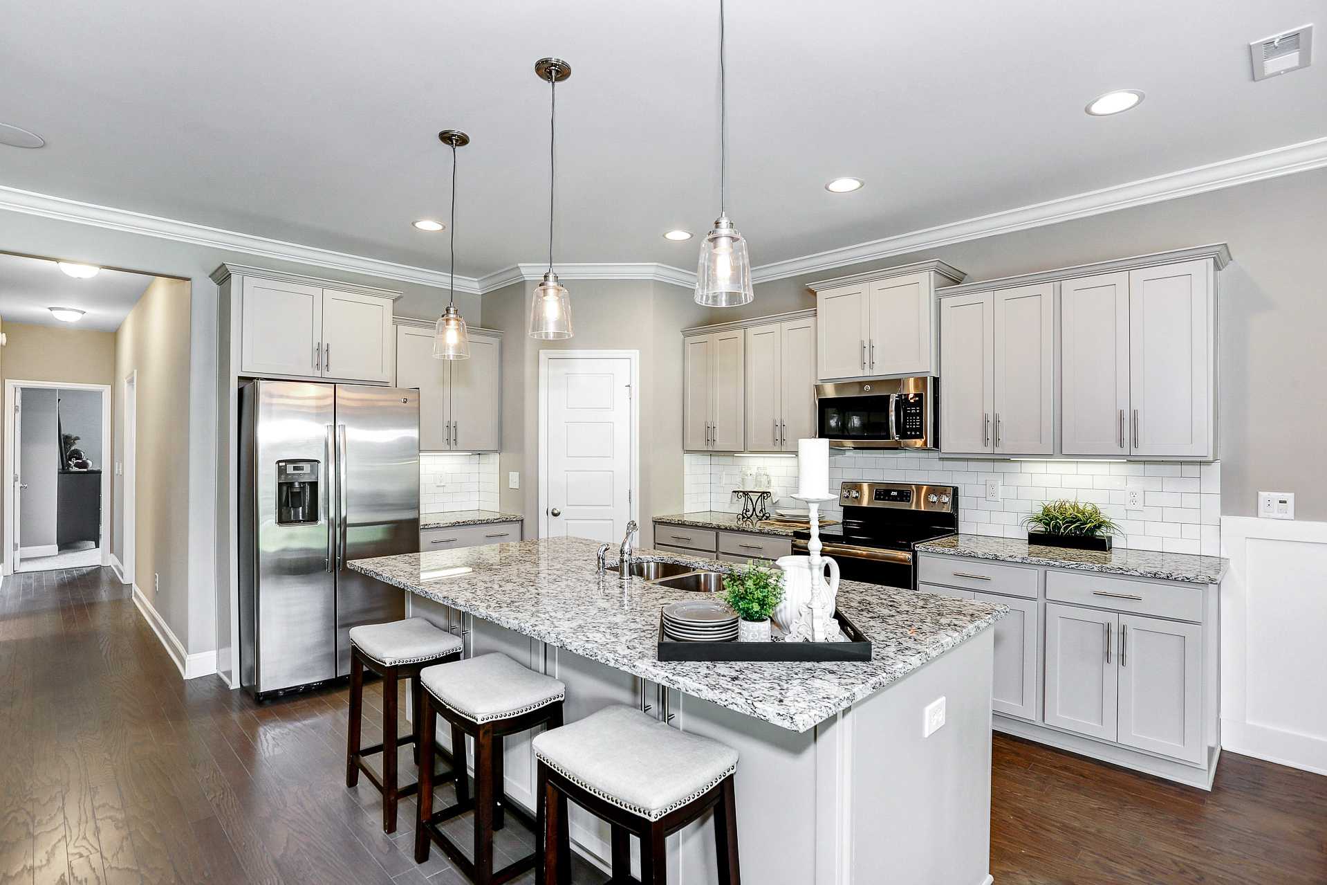 Modern white shaker kitchen at Stone Creek Phase II in Cullman Alabama with granite island, stainless appliances, pendant lights
