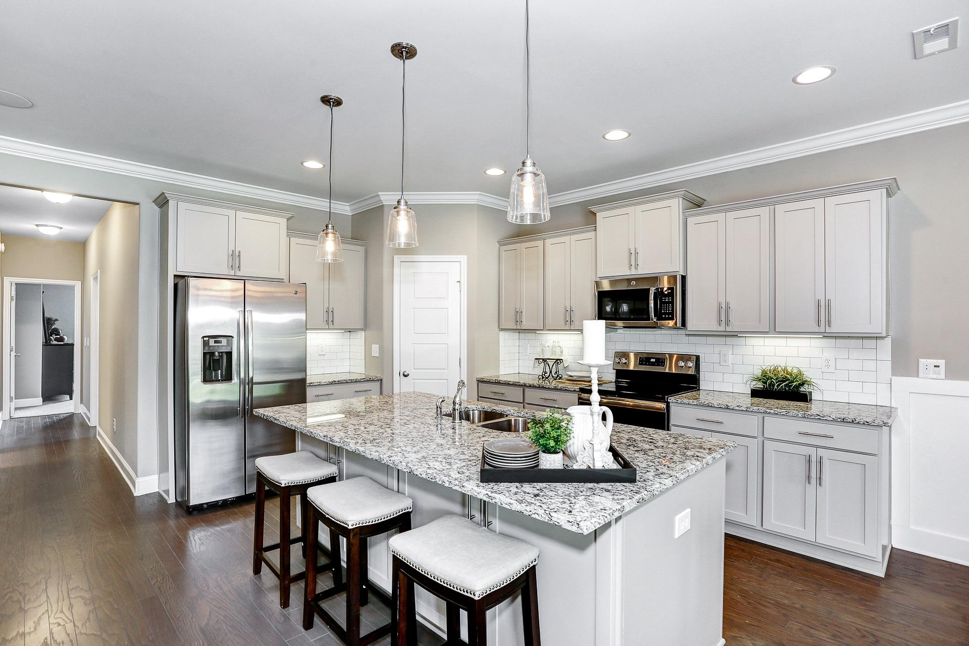 Modern white shaker kitchen at Stone Creek Phase II in Cullman Alabama with granite island, stainless appliances, pendant lights