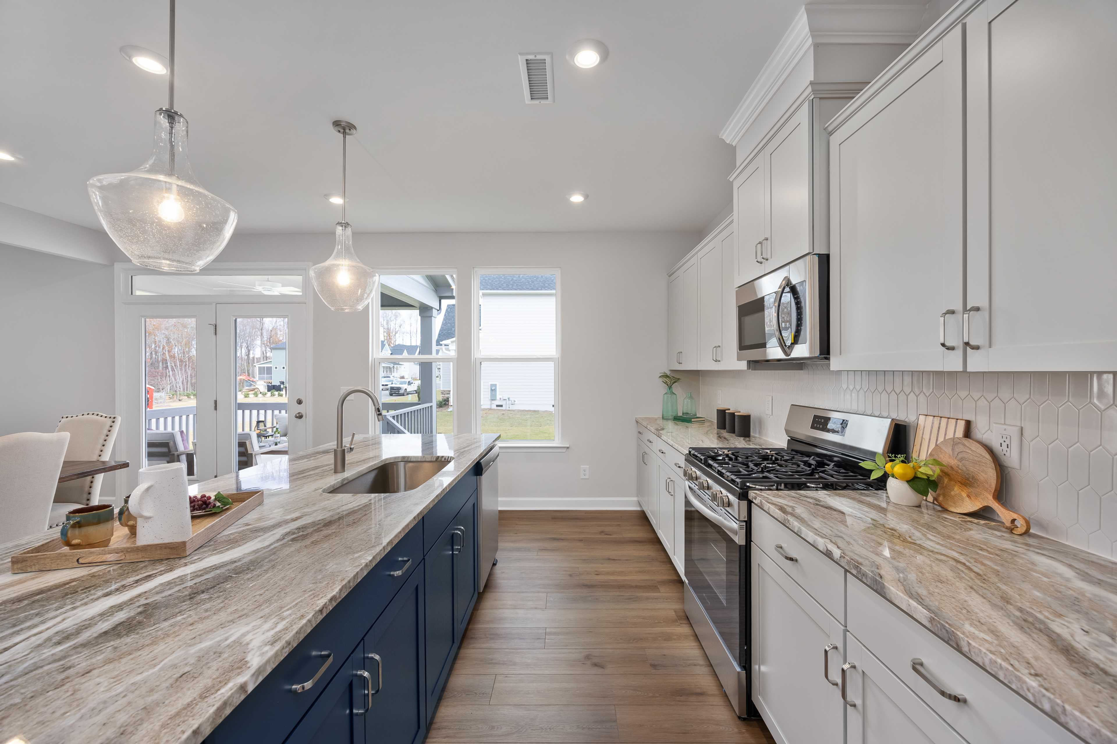 Modern kitchen at Enclave at Belmont in North Carolina featuring white cabinets, navy island, quartz counters and lake view