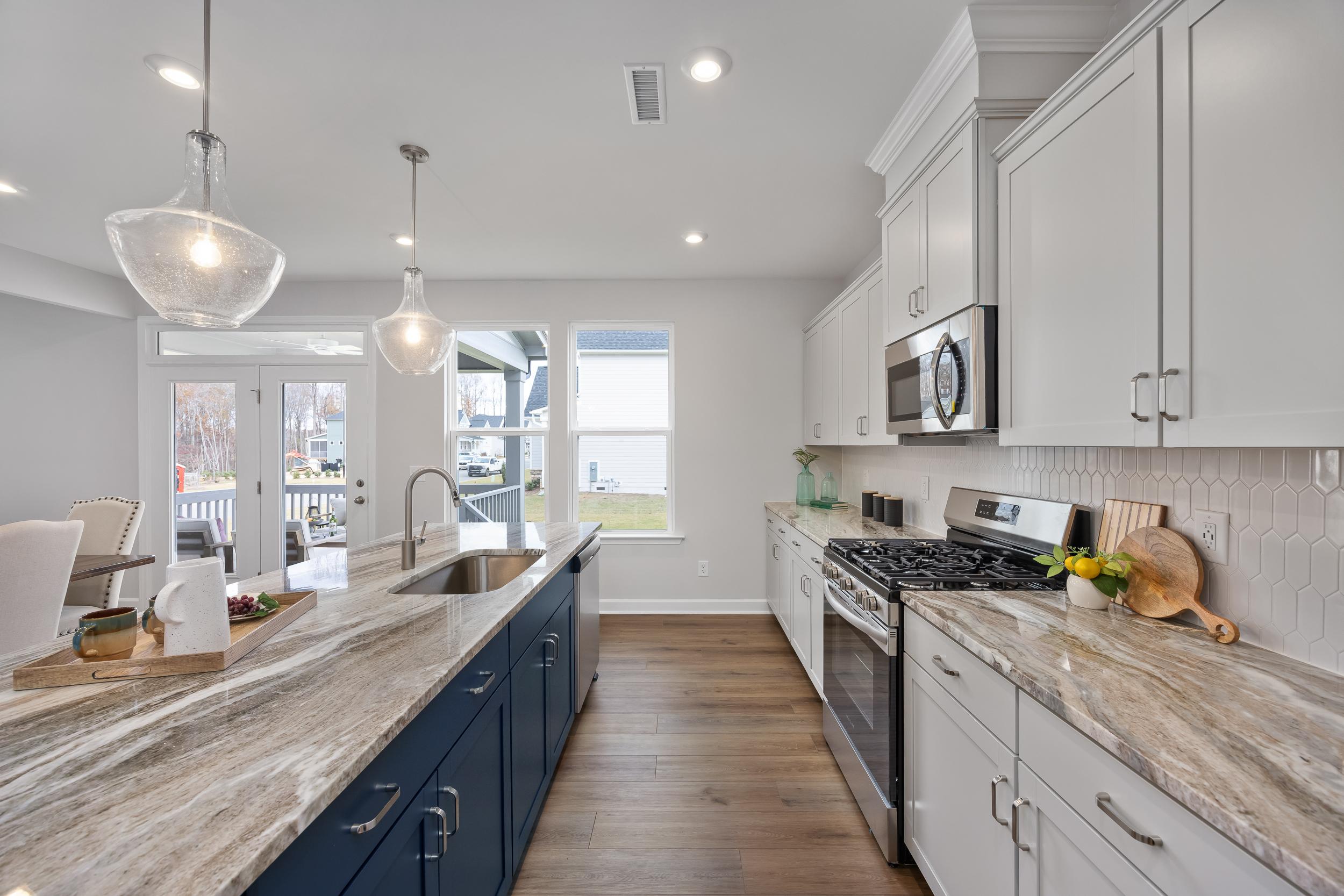 Modern kitchen at Enclave at Belmont in North Carolina featuring white cabinets, navy island, quartz counters and lake view