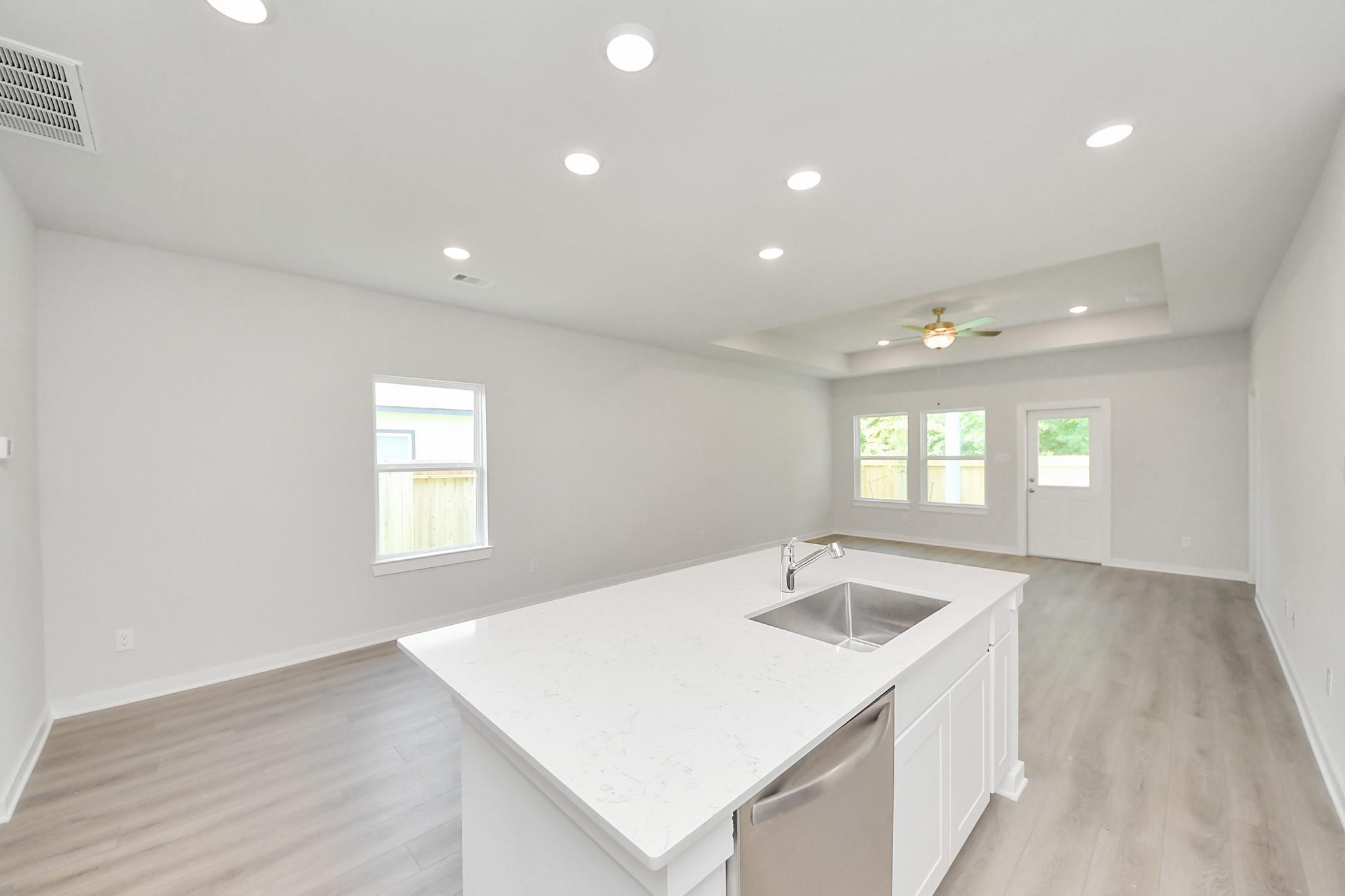 Open-concept kitchen with white quartz island in The Blanco E floor plan at Caney Creek Place, Conroe, Texas.
