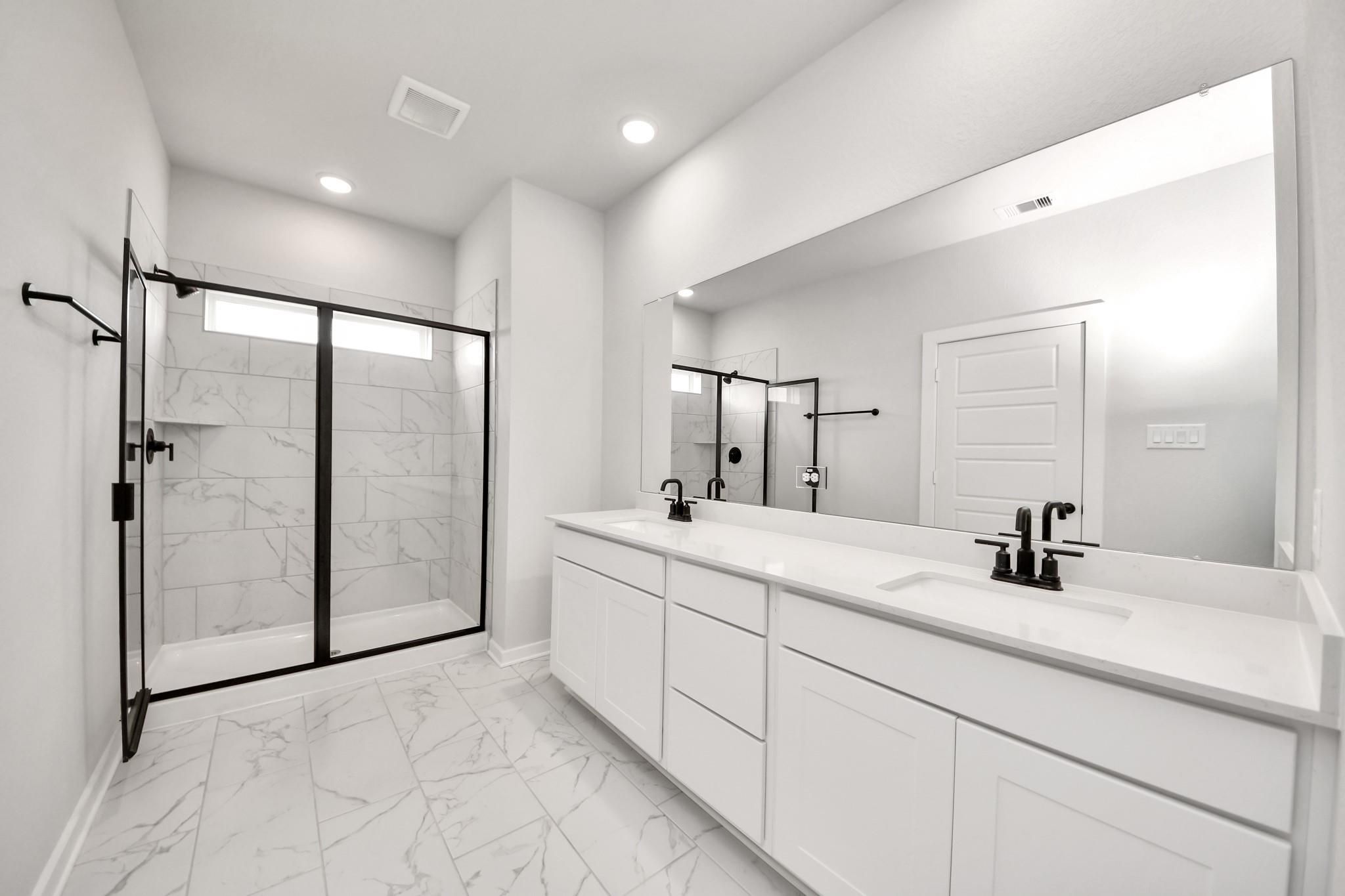 Modern master bathroom with dual vanity, marble-look tile, and glass shower in Davidson Homes Sorrento E, Sundance Cove.