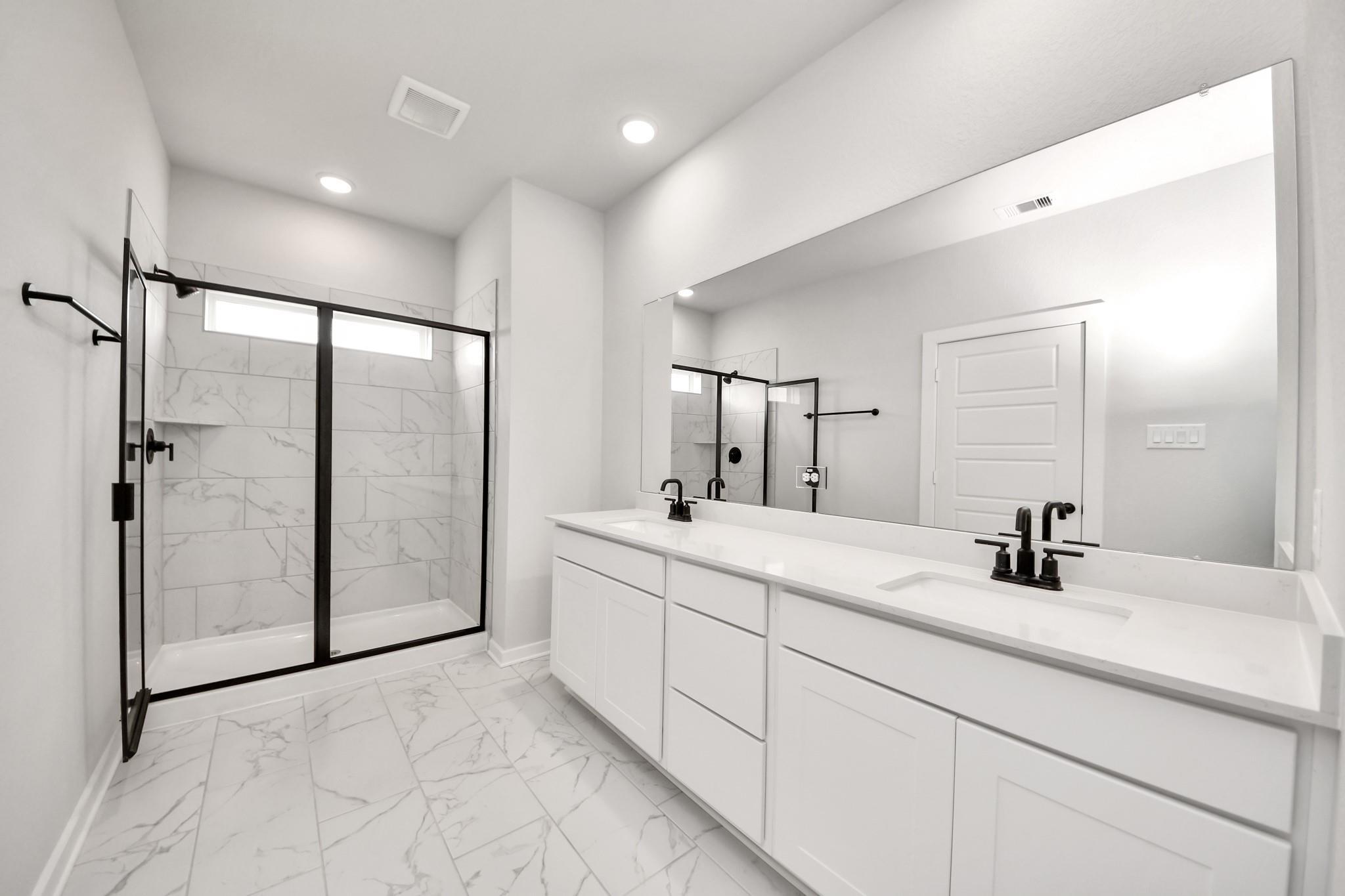 Modern master bathroom with dual vanity, marble-look tile, and glass shower in Davidson Homes Sorrento E, Sundance Cove.