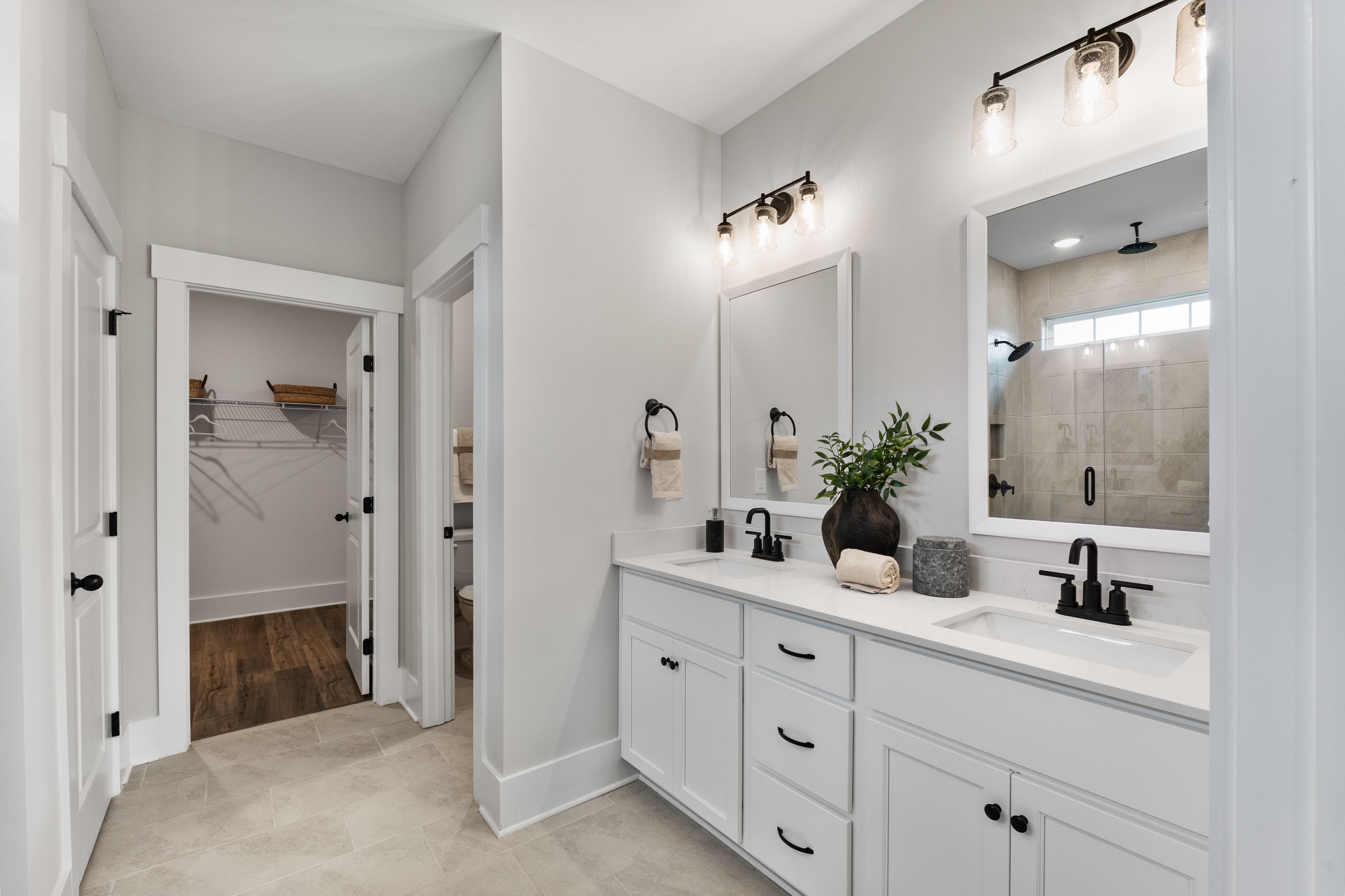 Primary bathroom at River Road Estates Decatur AL with double vanity white cabinets gray walls frameless glass shower walk-in closet