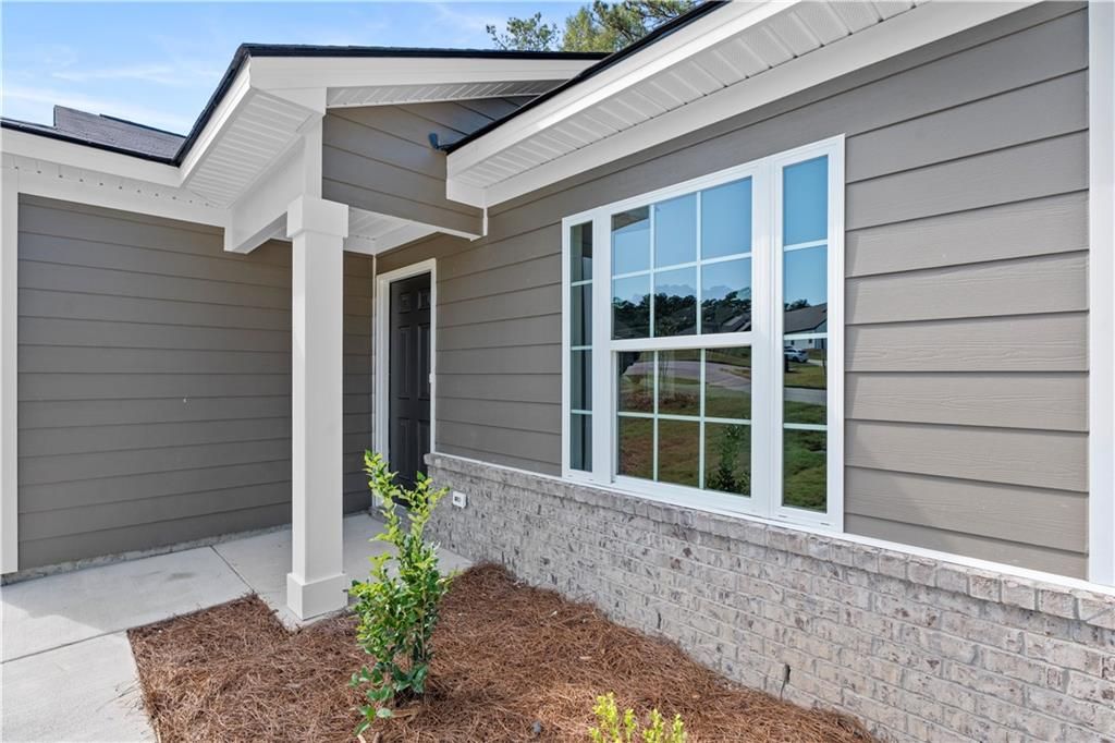 Modern gray-sided single-story home with white-trimmed windows, covered entry porch, and brick base in Phenix City, Alabama