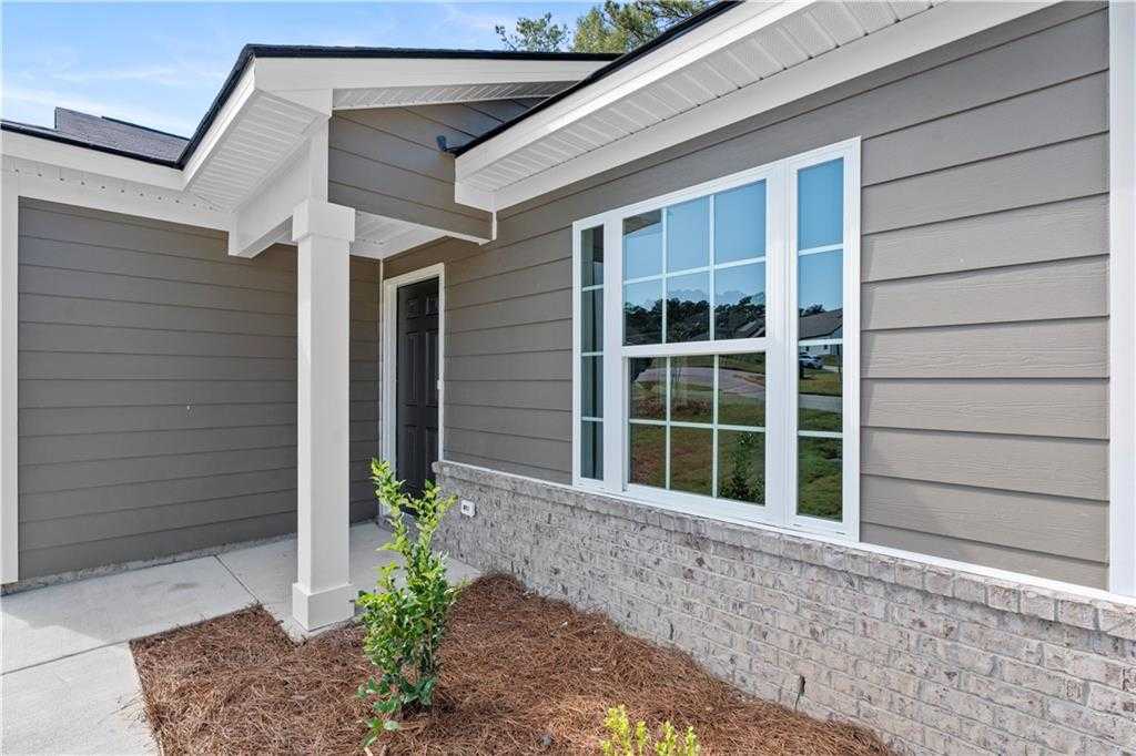 Modern gray-sided single-story home with white-trimmed windows, covered entry porch, and brick base in Phenix City, Alabama