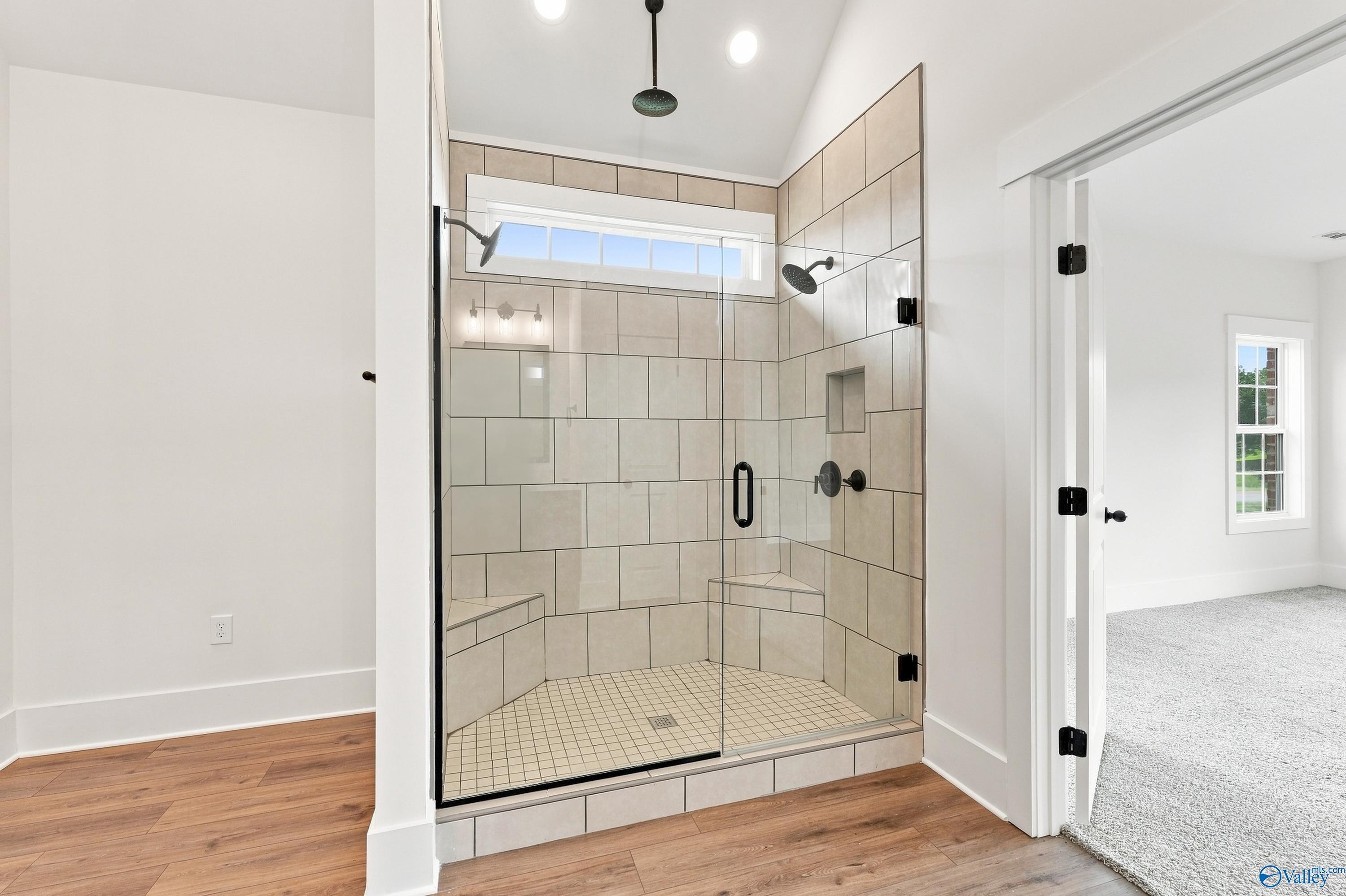 Tile walk-in shower with glass door, dual shower heads, and built-in bench in The Valencia master bath, Huntsville, AL
