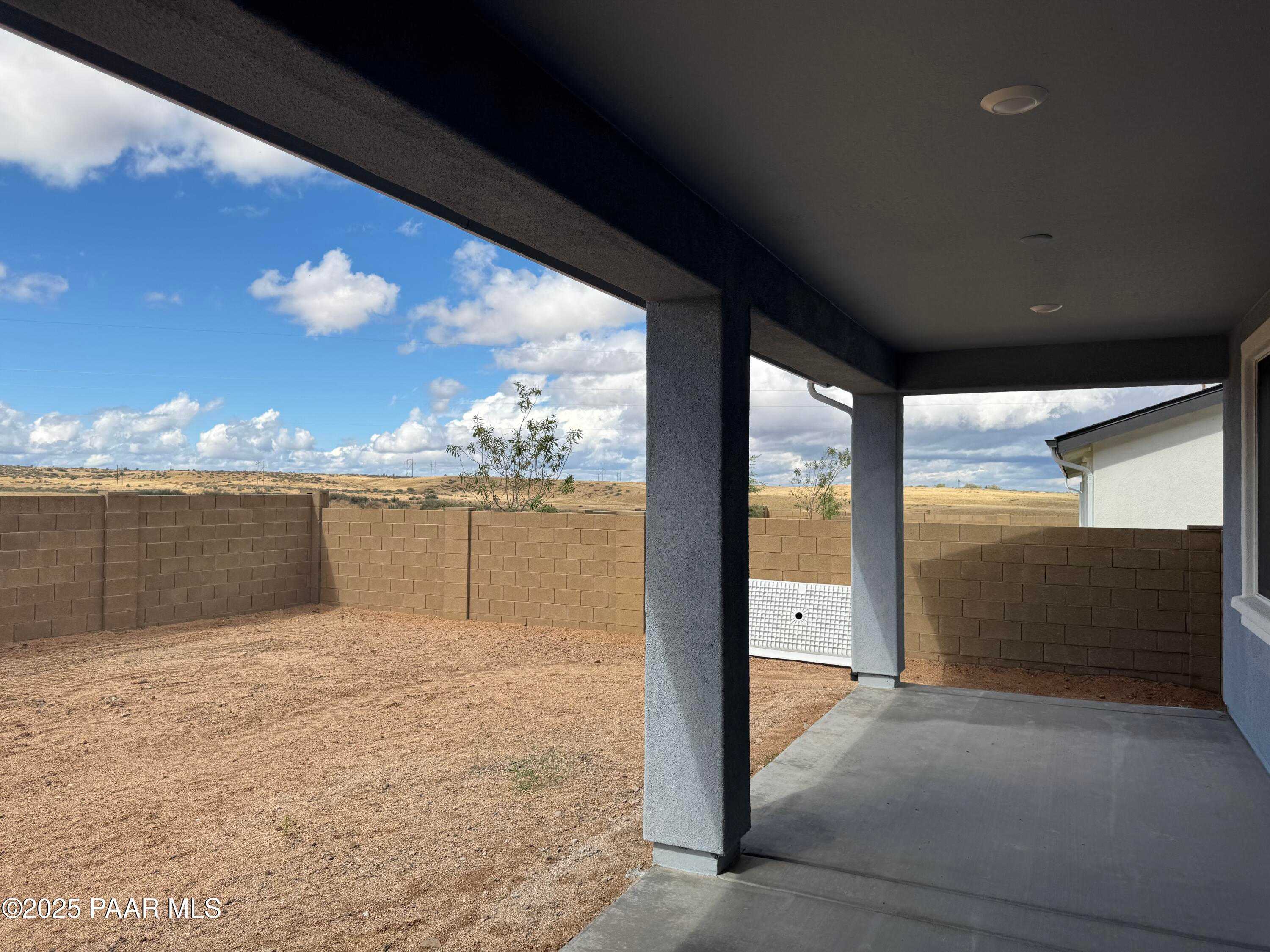 Covered back patio with desert backyard, block walls, and mountain views in Westwood, Prescott, Arizona home