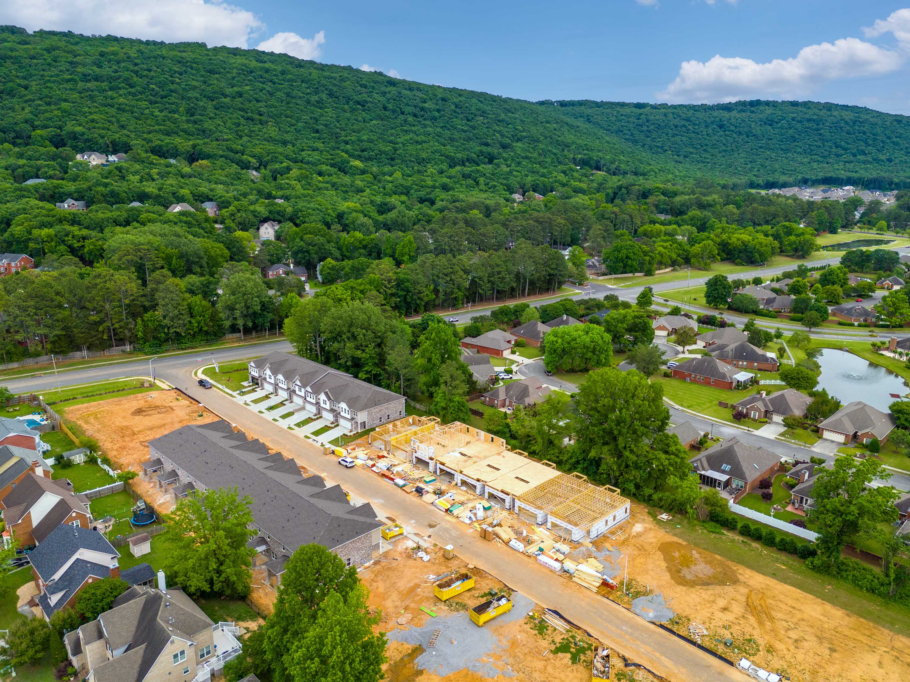 Aerial view of townhome construction at The Pavilion in Huntsville AL amid lush forests hills and nearby homes