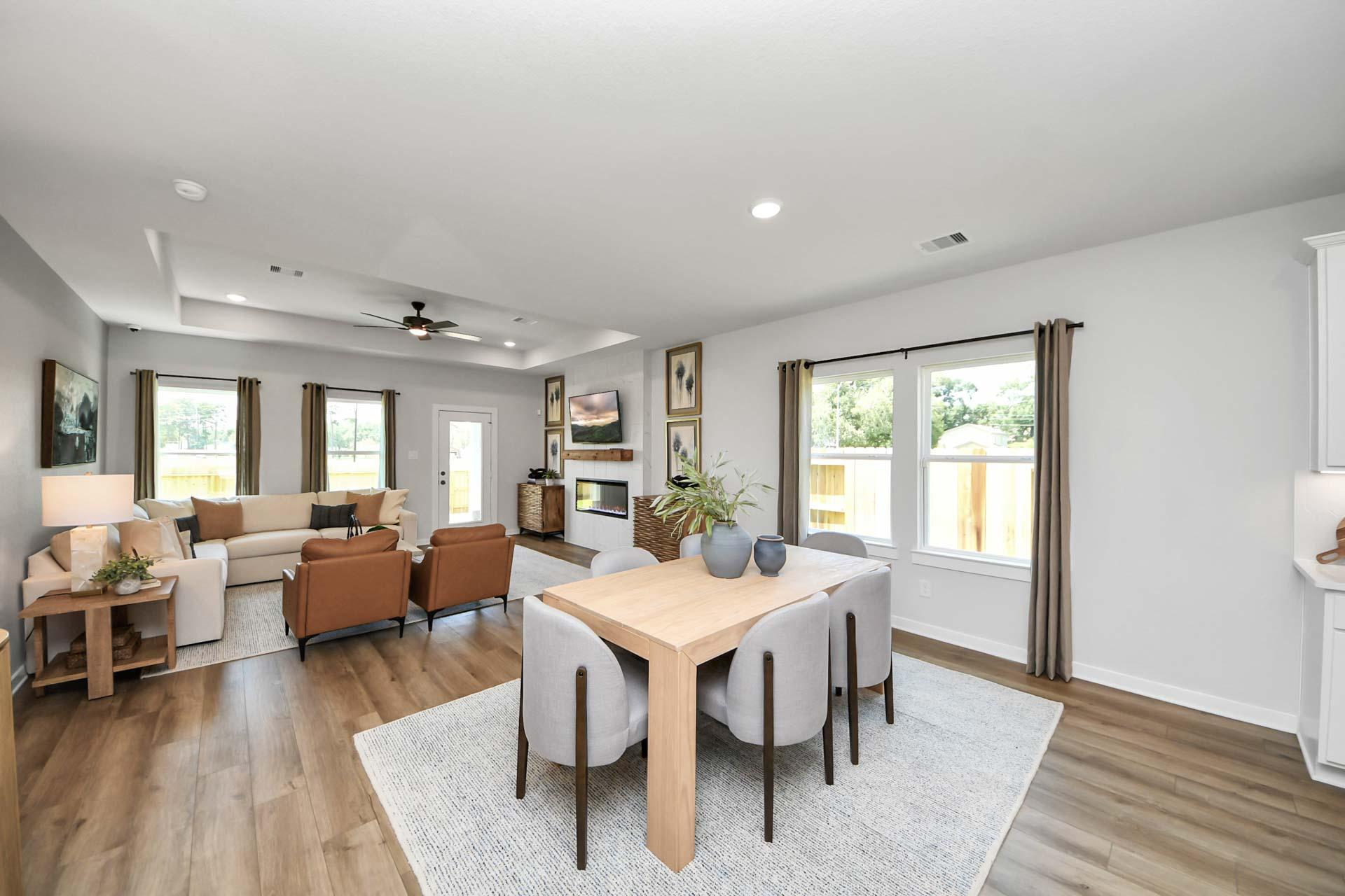 Open-concept living and dining area at Enclave at Newport in Crosby, Texas, featuring hardwood floors and modern decor.