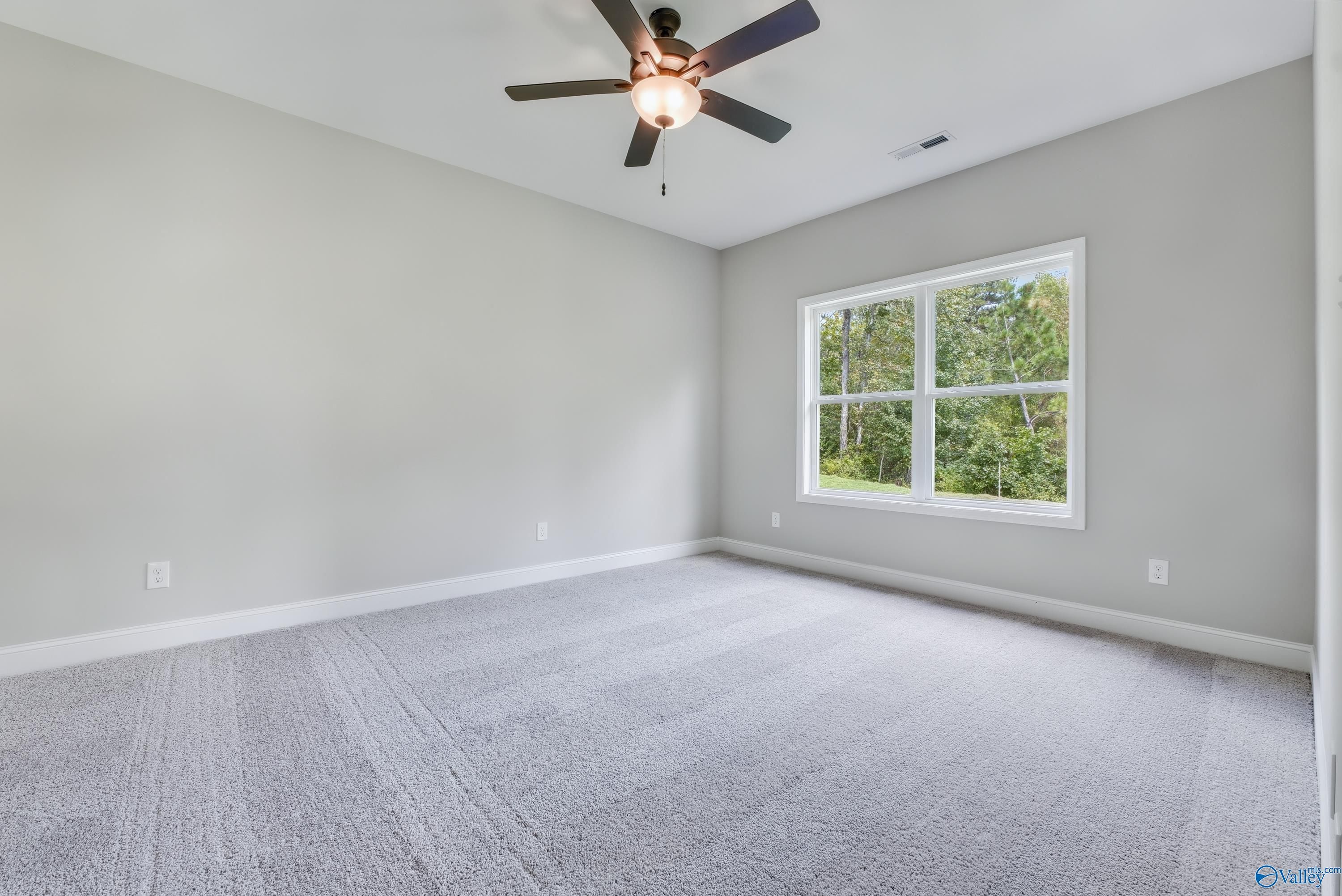Bright secondary bedroom featuring gray walls, ceiling fan, and large window with tree views in Davidson Homes The Franklin, Huntsville AL