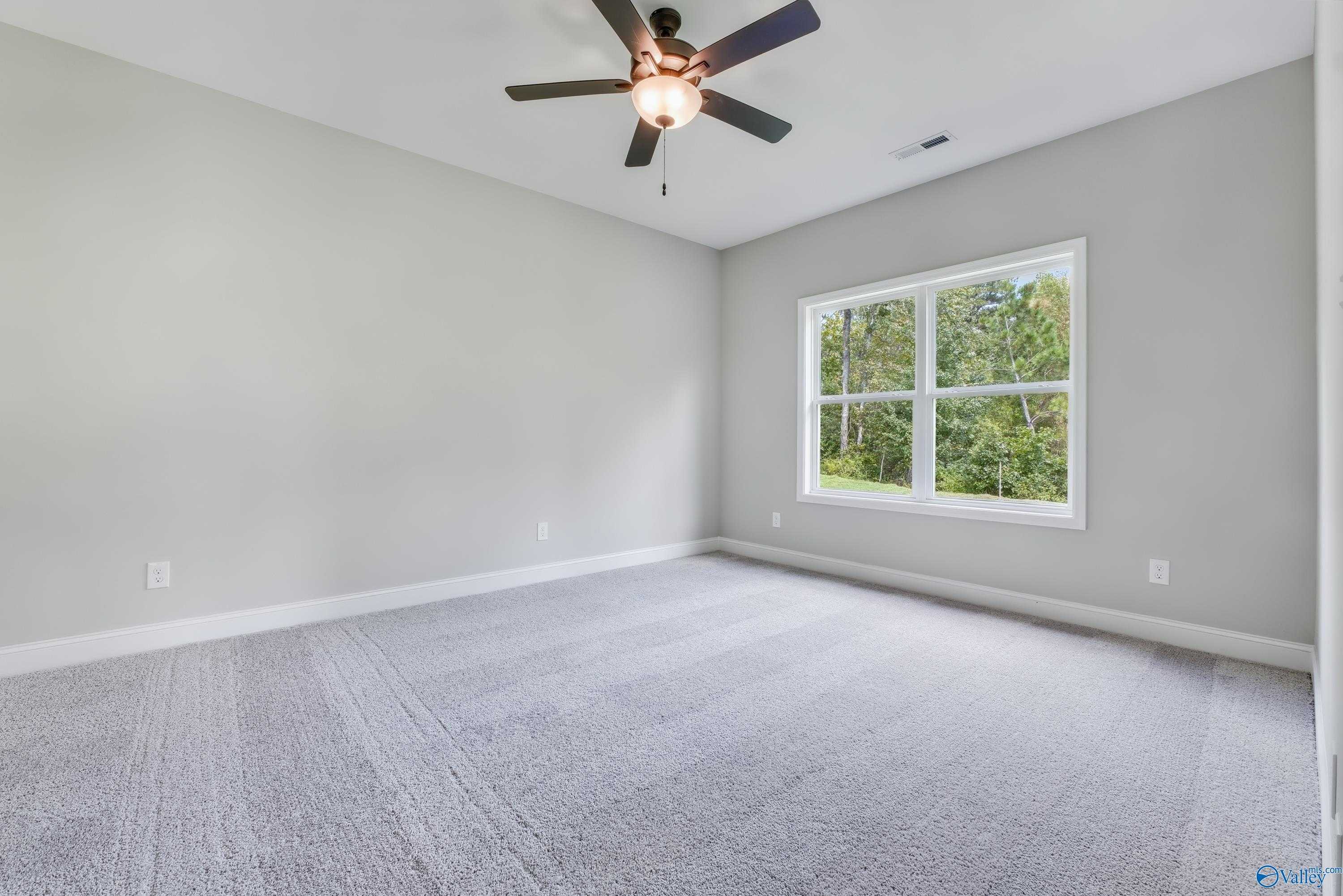 Bright secondary bedroom featuring gray walls, ceiling fan, and large window with tree views in Davidson Homes The Franklin, Huntsville AL