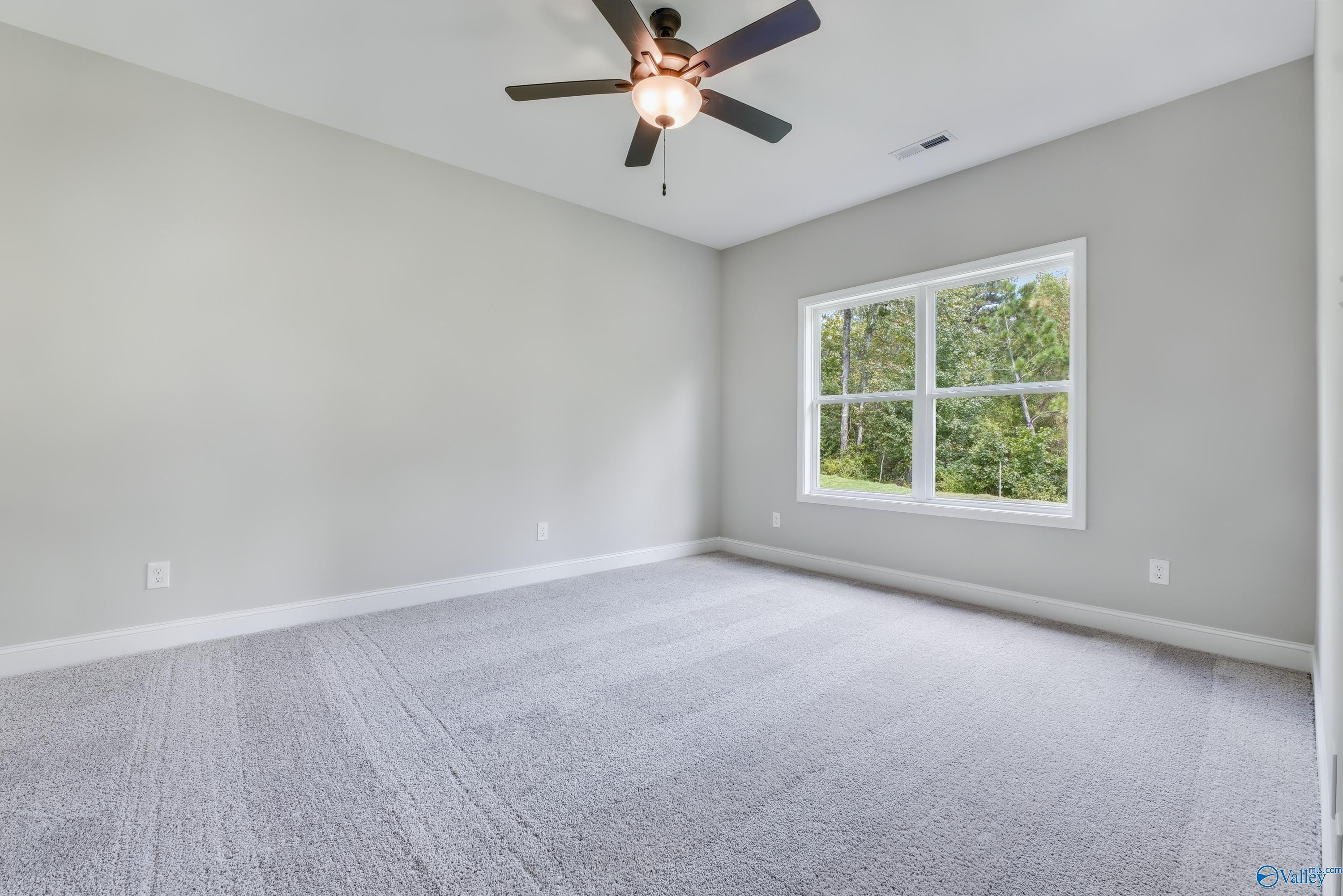 Bright secondary bedroom featuring gray walls, ceiling fan, and large window with tree views in Davidson Homes The Franklin, Huntsville AL