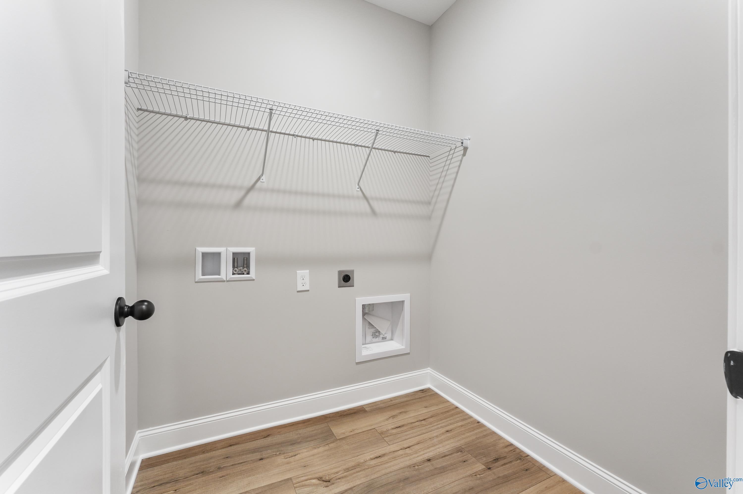 Functional laundry room with wire shelving, washer/dryer hookups, and hardwood floors in Davidson Homes The Asheville C, Meridianville, Alabama