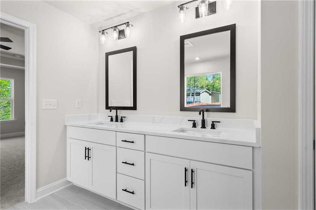 Modern master bathroom with double white vanity, black mirrors, and natural light in Davidson Homes The Hickory B, Buford, GA