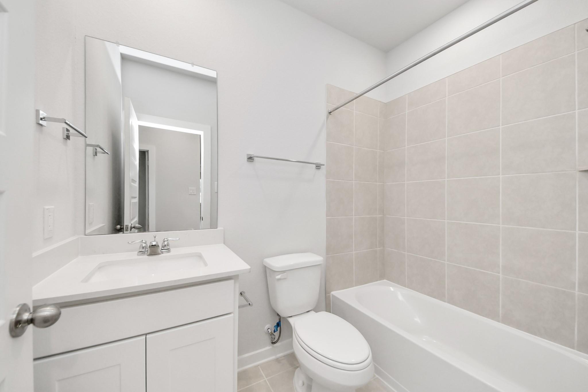 Modern bathroom with white vanity, chrome fixtures, and tiled tub-shower in The Frio floor plan at Liberty Estates.