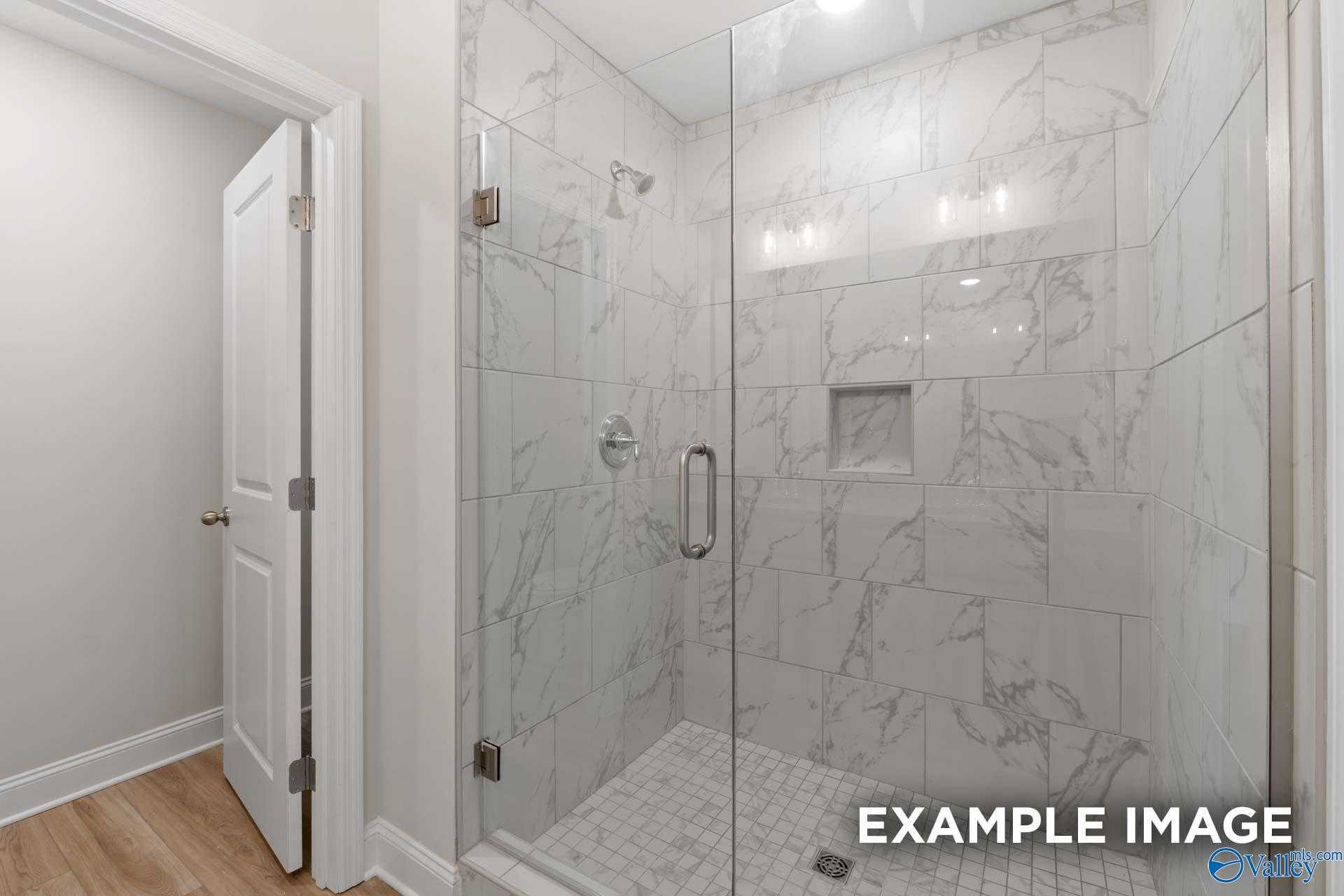 Elegant frameless glass shower with white marble tiles and niche shelf in master bath, Davidson Homes The Camden, Huntsville AL