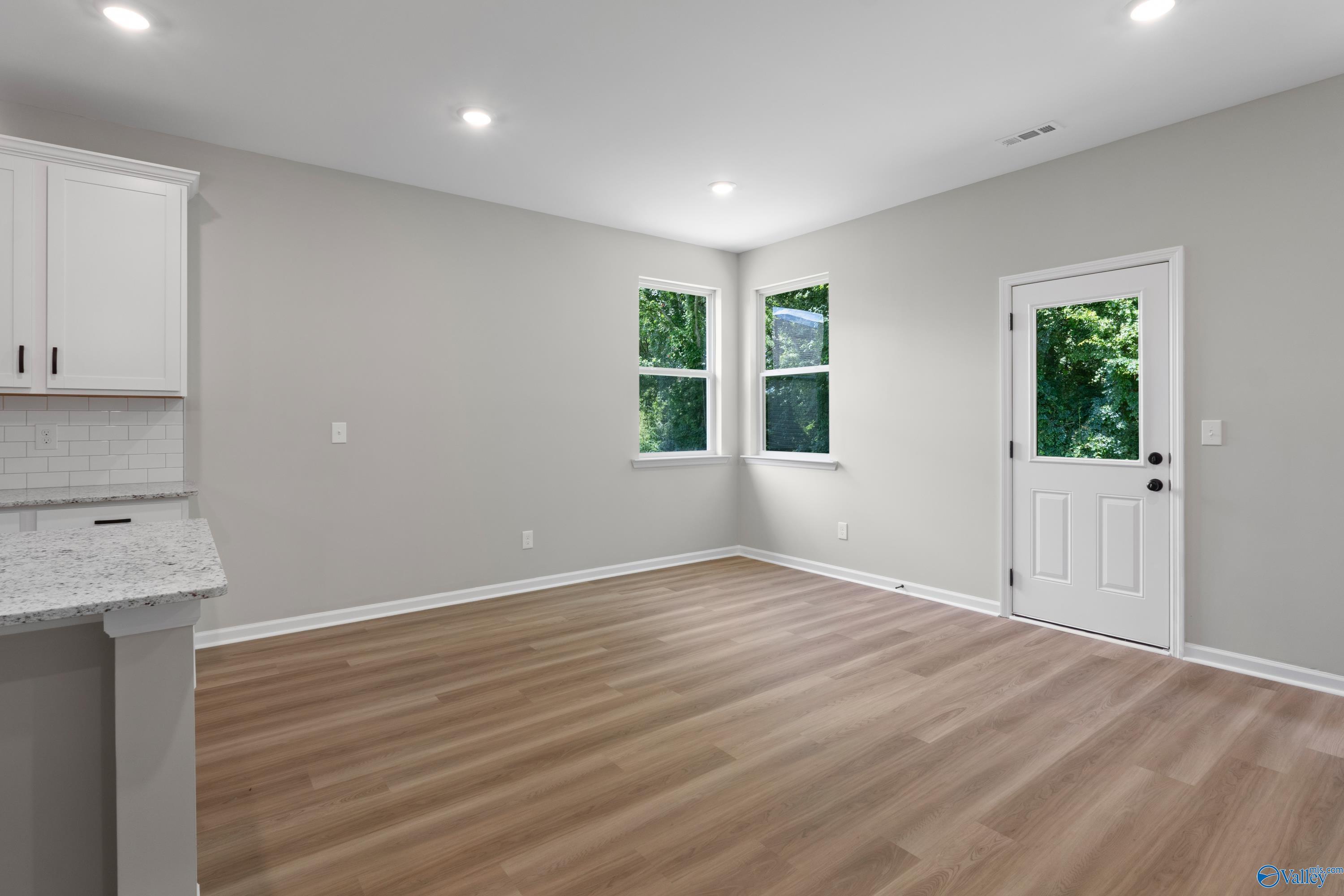 Bright breakfast nook with granite bar, white cabinets, laminate wood floors, and large windows in Davidson Homes The Phoenix, Hazel Green