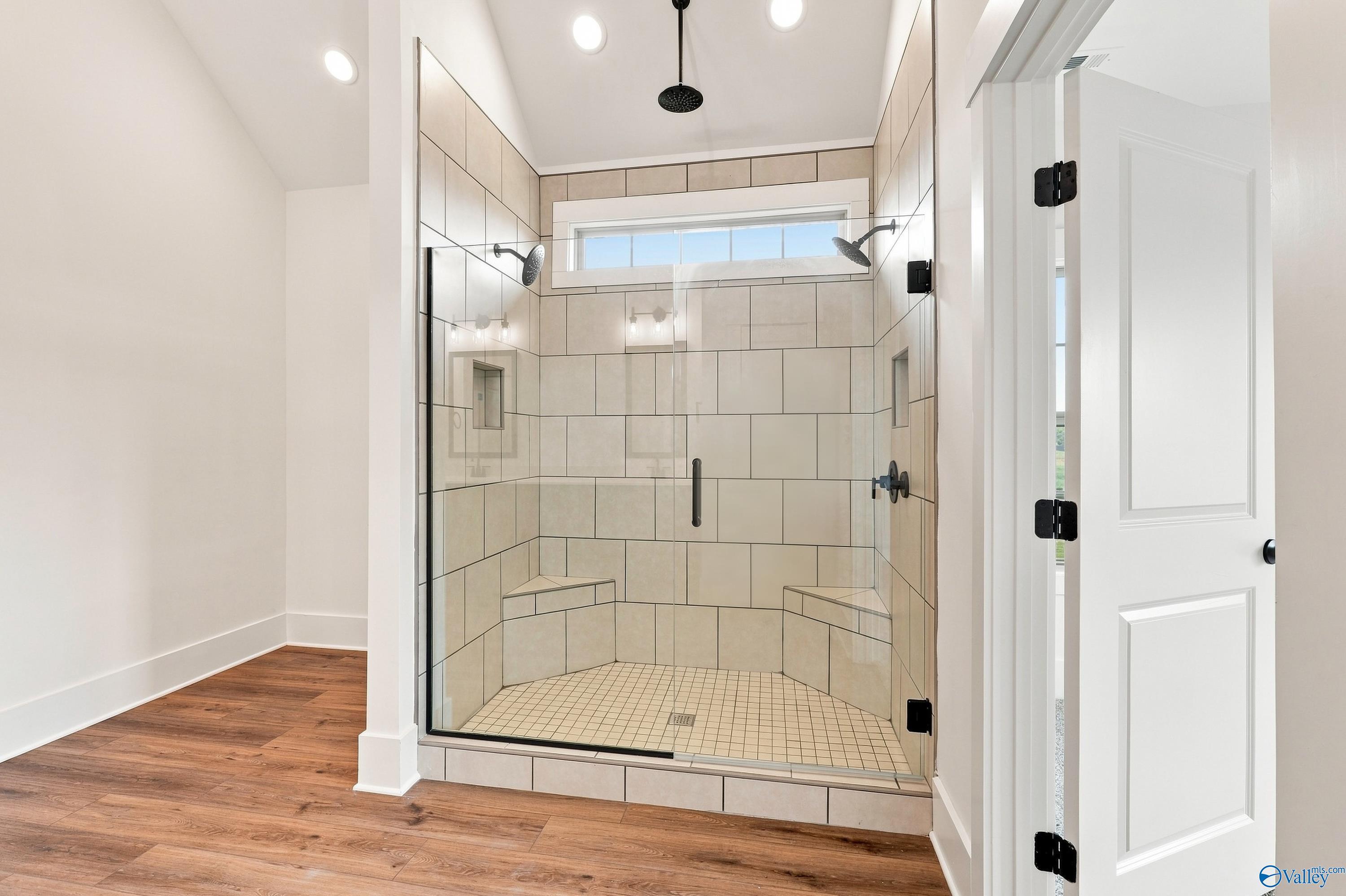 Spacious walk-in shower with dual showerheads, tile bench seating, and matte black fixtures in Davidson Homes Valencia master bath, Huntsville