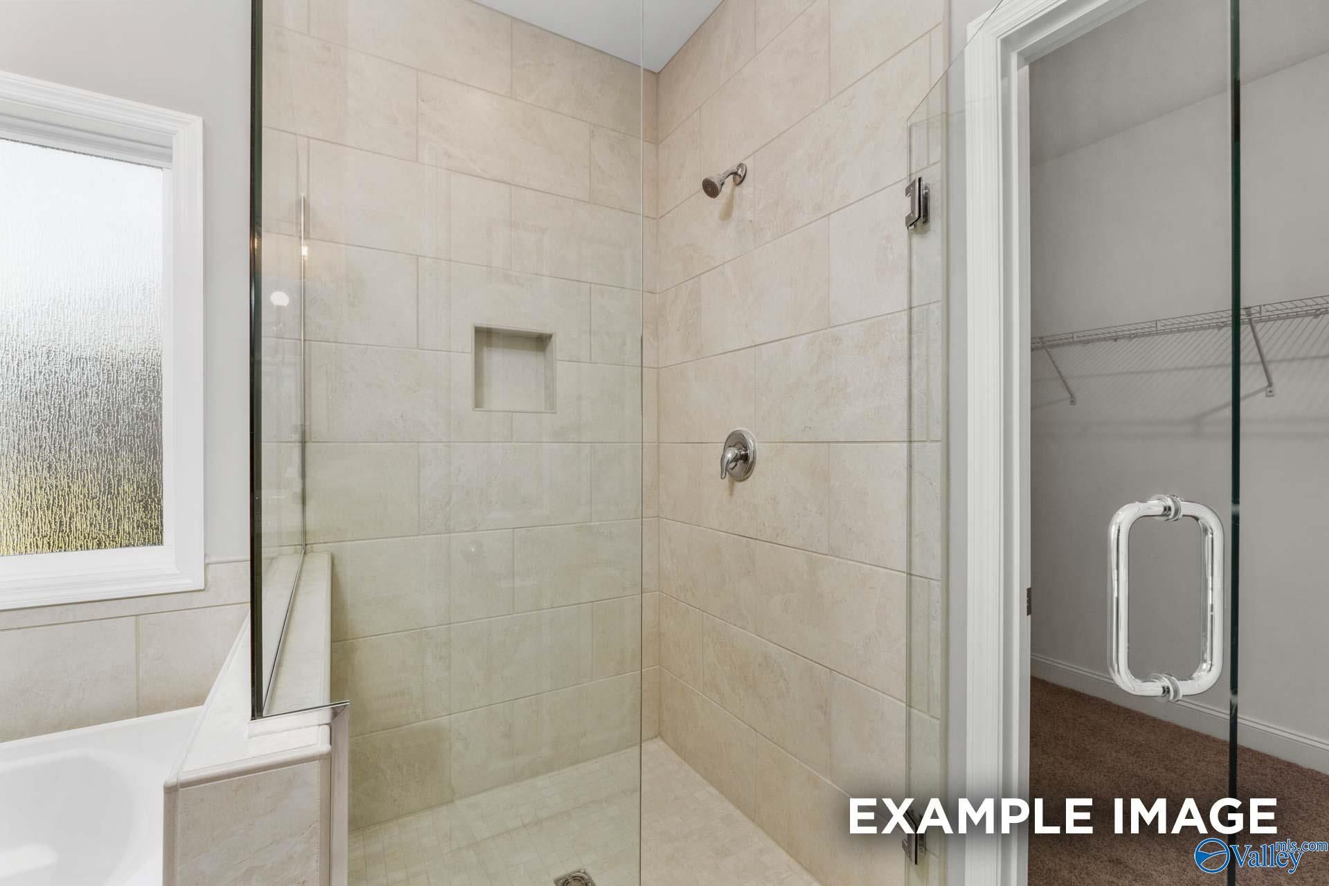 Tiled walk-in shower with glass door and soaking tub in master bathroom of Davidson Homes Harrison B plan in Athens, Alabama