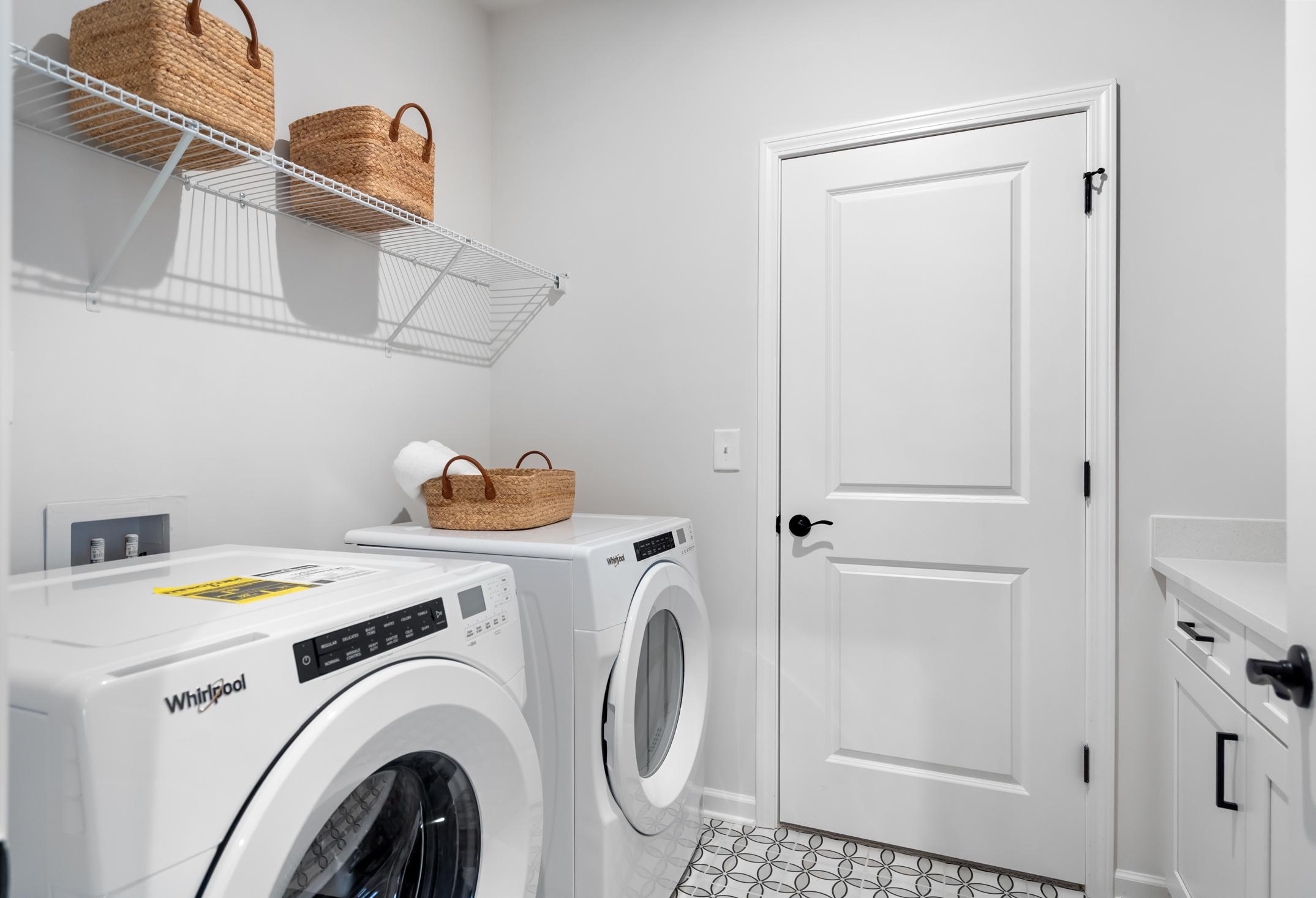 Modern laundry room in The Edison C by Davidson Homes featuring Whirlpool washer dryer and wicker basket shelves