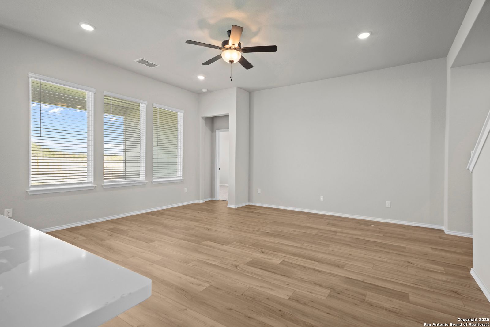 Bright living room with hardwood floors, large windows, and ceiling fan in The Sequoia A by Davidson Homes, Converse, Texas