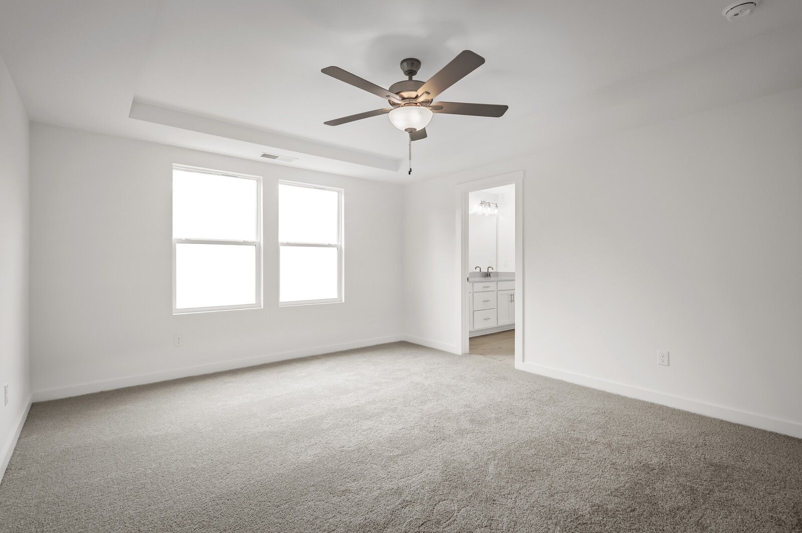 Spacious bedroom with tray ceiling and ceiling fan in The Logan C floor plan at Calista Farms in White House, Tennessee.