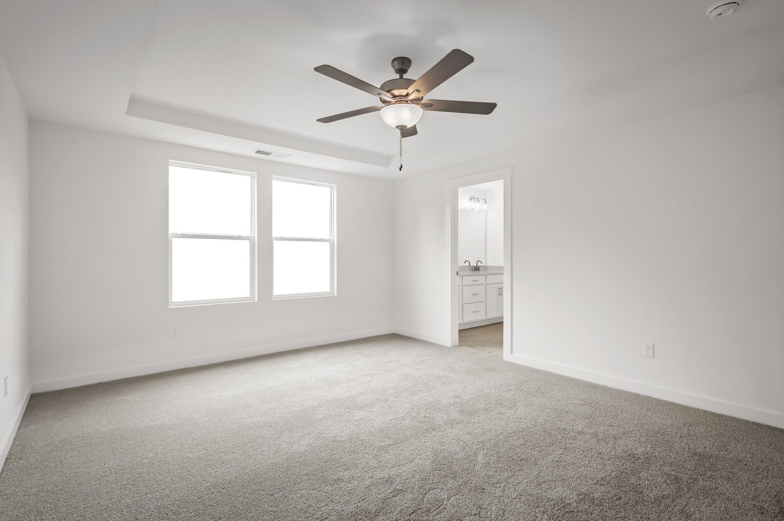 Spacious bedroom with tray ceiling and ceiling fan in The Logan C floor plan at Calista Farms in White House, Tennessee.