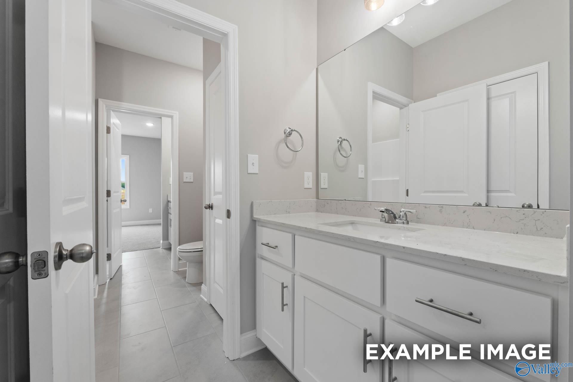 Bright guest bathroom with white shaker vanity, quartz countertop, mirror, and tiled floor in Davidson Homes The Finleigh, Harvest AL