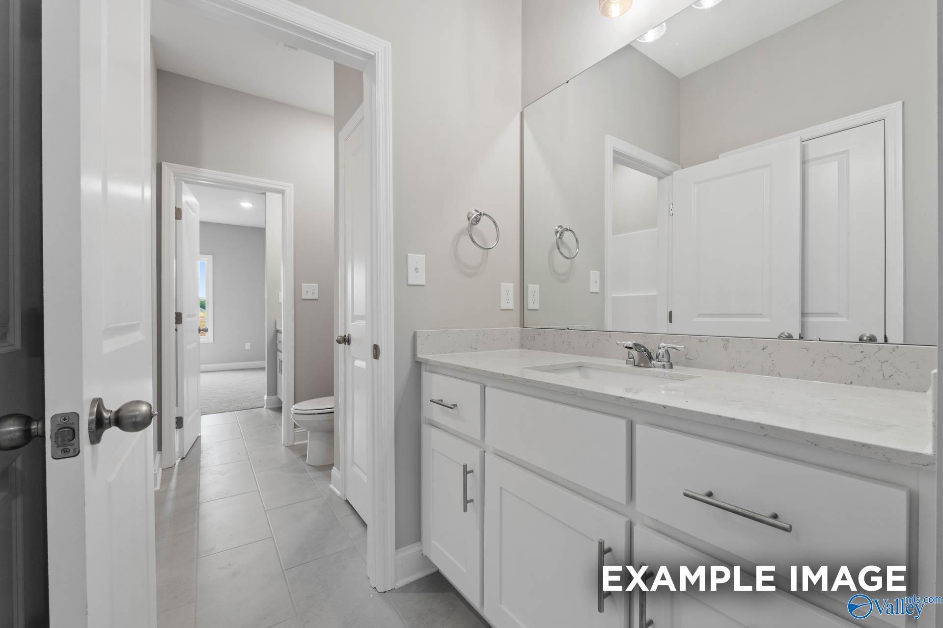Bright guest bathroom with white shaker vanity, quartz countertop, mirror, and tiled floor in Davidson Homes The Finleigh, Harvest AL