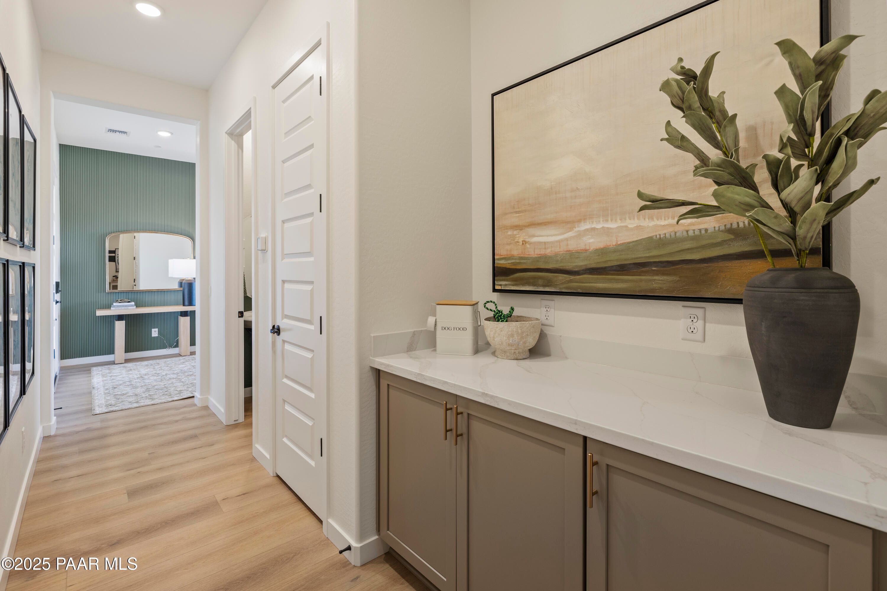 Elegant hallway with abstract landscape painting, white quartz console table, and potted greenery in Davidson Homes The Blaze D, Prescott AZ