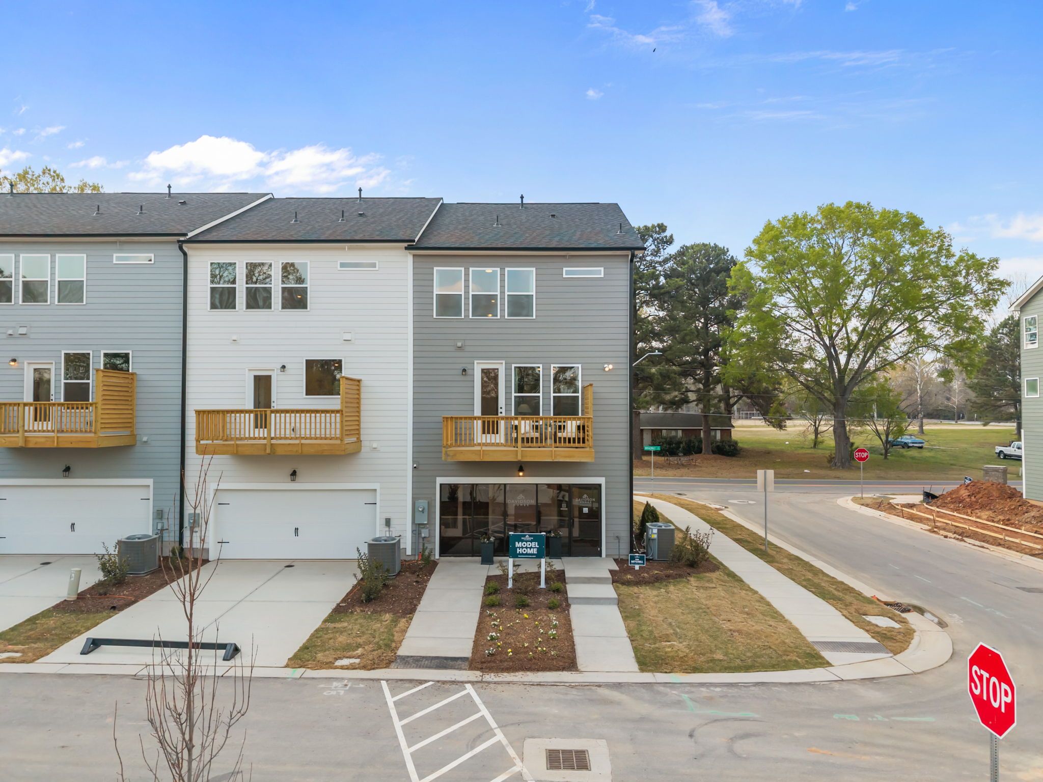 Modern townhomes at Camden Park in Knightdale, NC with gray-white exteriors, wooden balconies, and garages