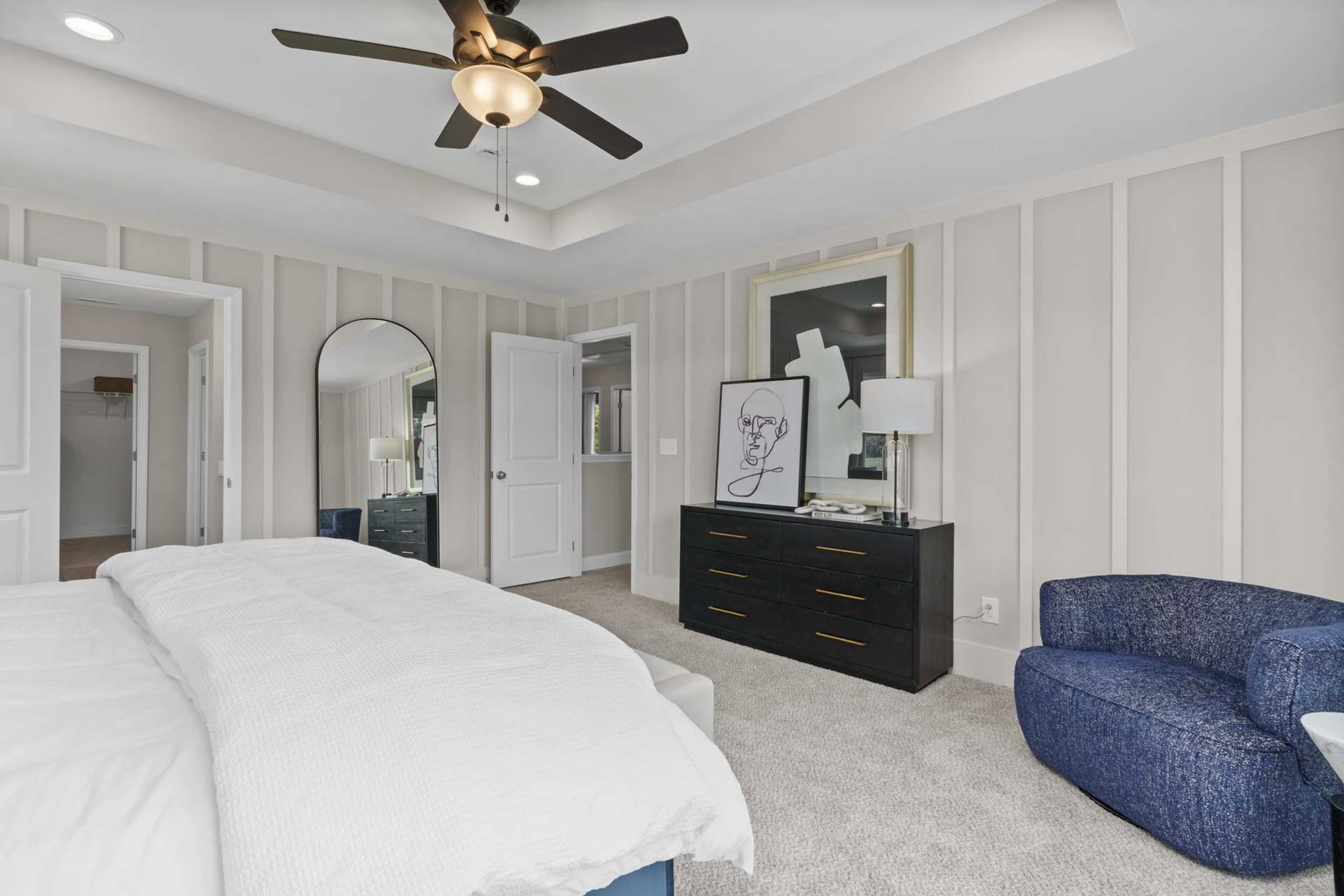 Spacious master bedroom in Creek Grove, New Market Alabama with king bed, ceiling fan, shiplap walls and blue accent chair