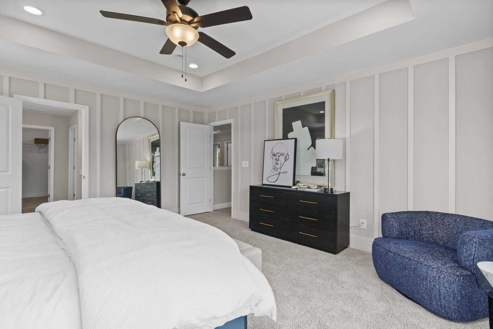 Spacious master bedroom in Creek Grove, New Market Alabama with king bed, ceiling fan, shiplap walls and blue accent chair