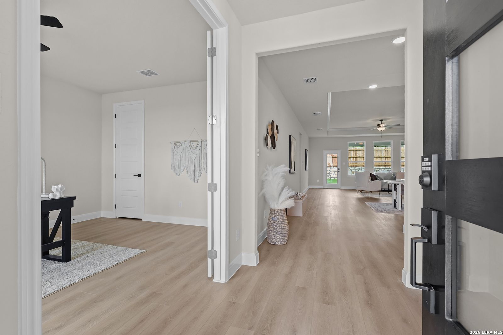 Bright entryway with open doors to living area, hardwood floors, and modern decor in The Lanier G by Davidson Homes, Castroville Texas