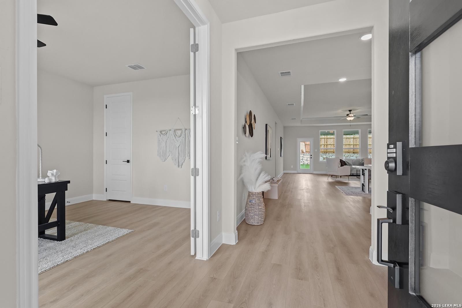 Bright entryway with open doors to living area, hardwood floors, and modern decor in The Lanier G by Davidson Homes, Castroville Texas