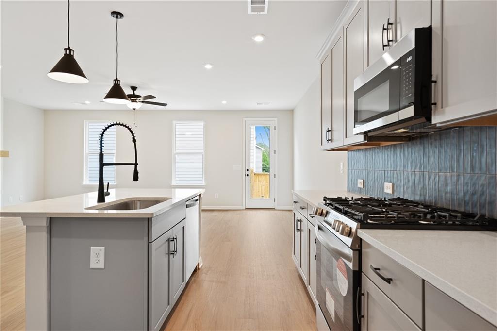 Modern open-concept kitchen with gray island, blue subway tile backsplash, stainless appliances in Davidson Homes The Marion A, Kennesaw, GA