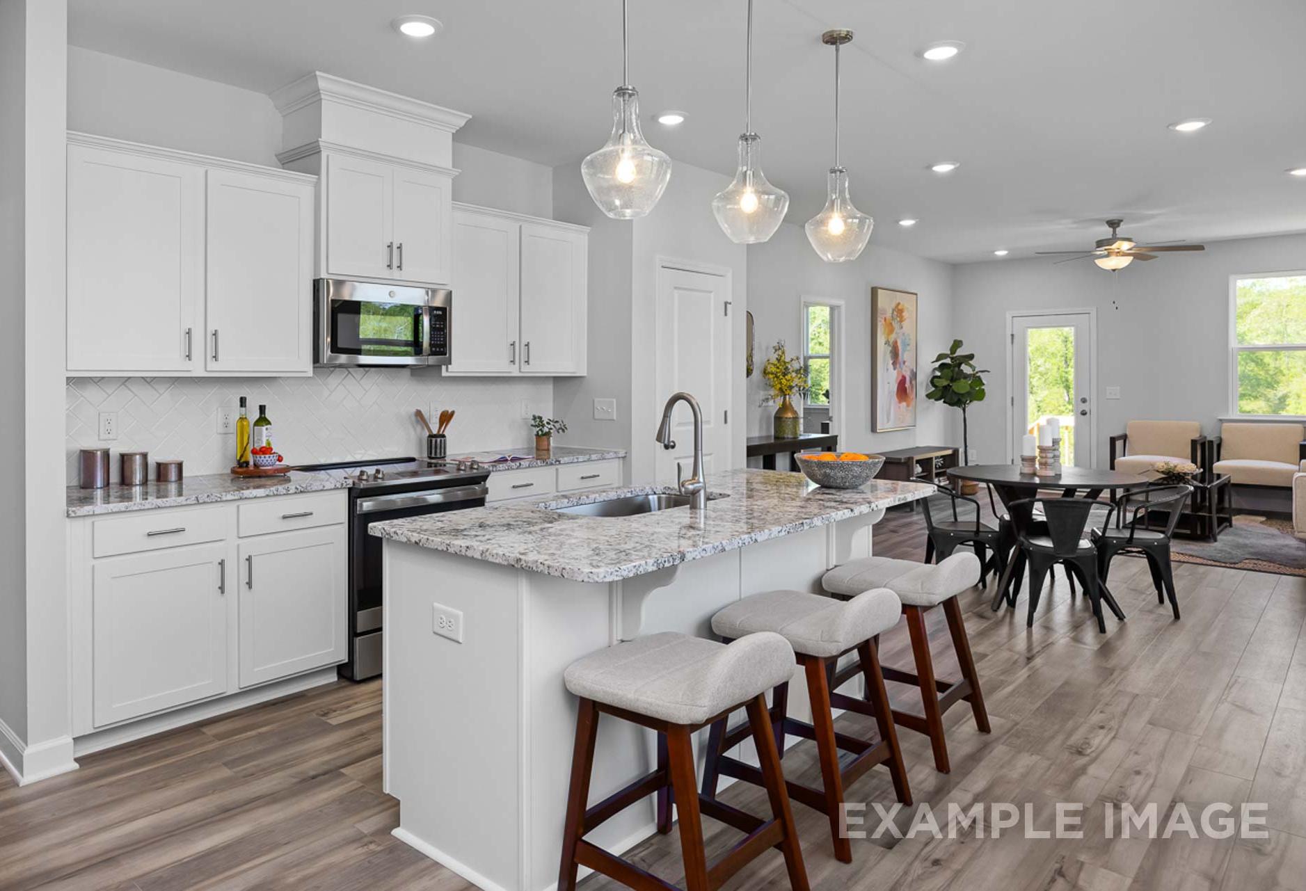 Modern Carter B kitchen by Davidson Homes featuring white cabinets, granite island with bar stools, open to dining and living areas