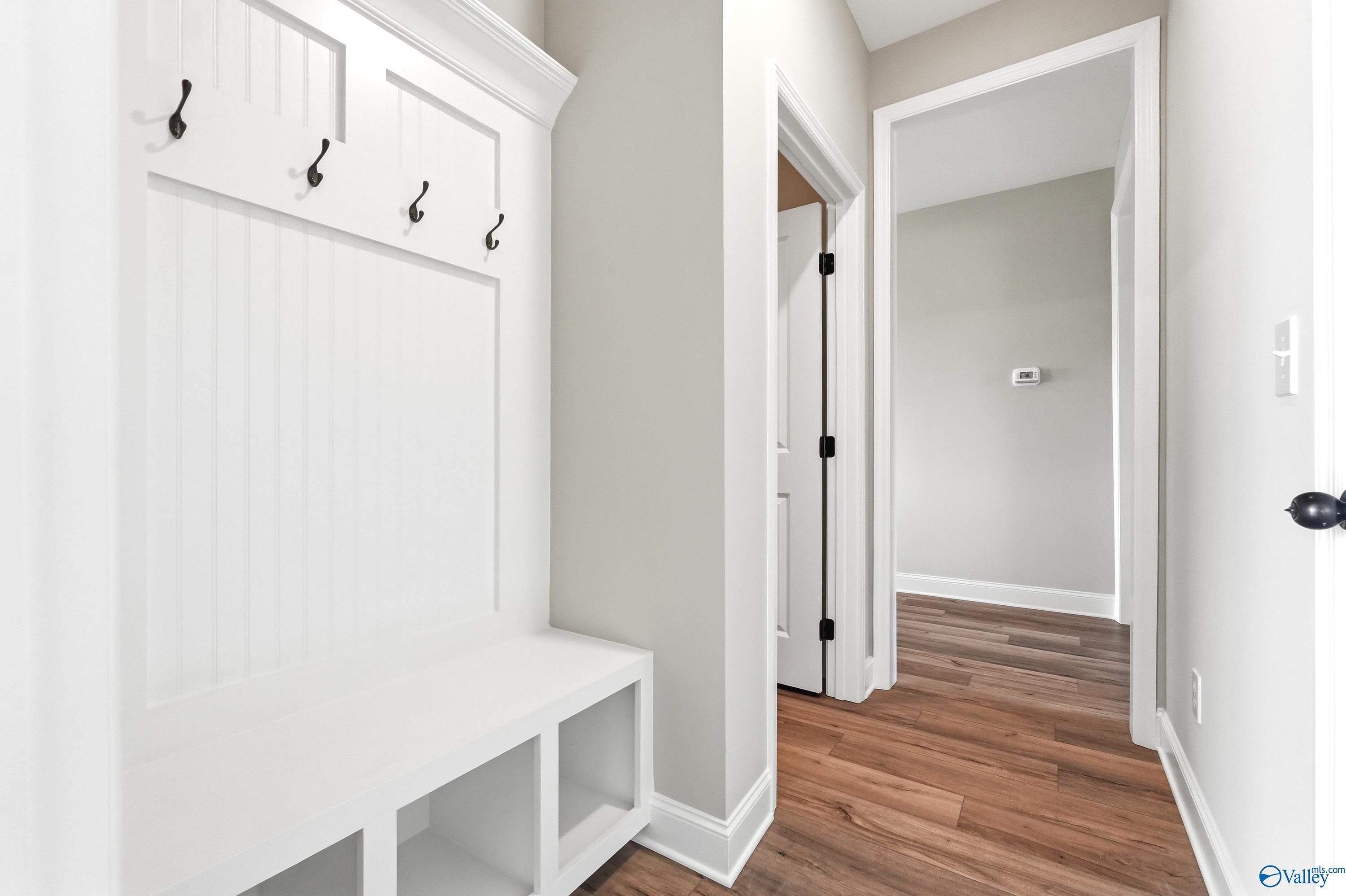 White mudroom bench with coat hooks in The Daphne D floor plan by Davidson Homes in Creekside, Harvest, Alabama.