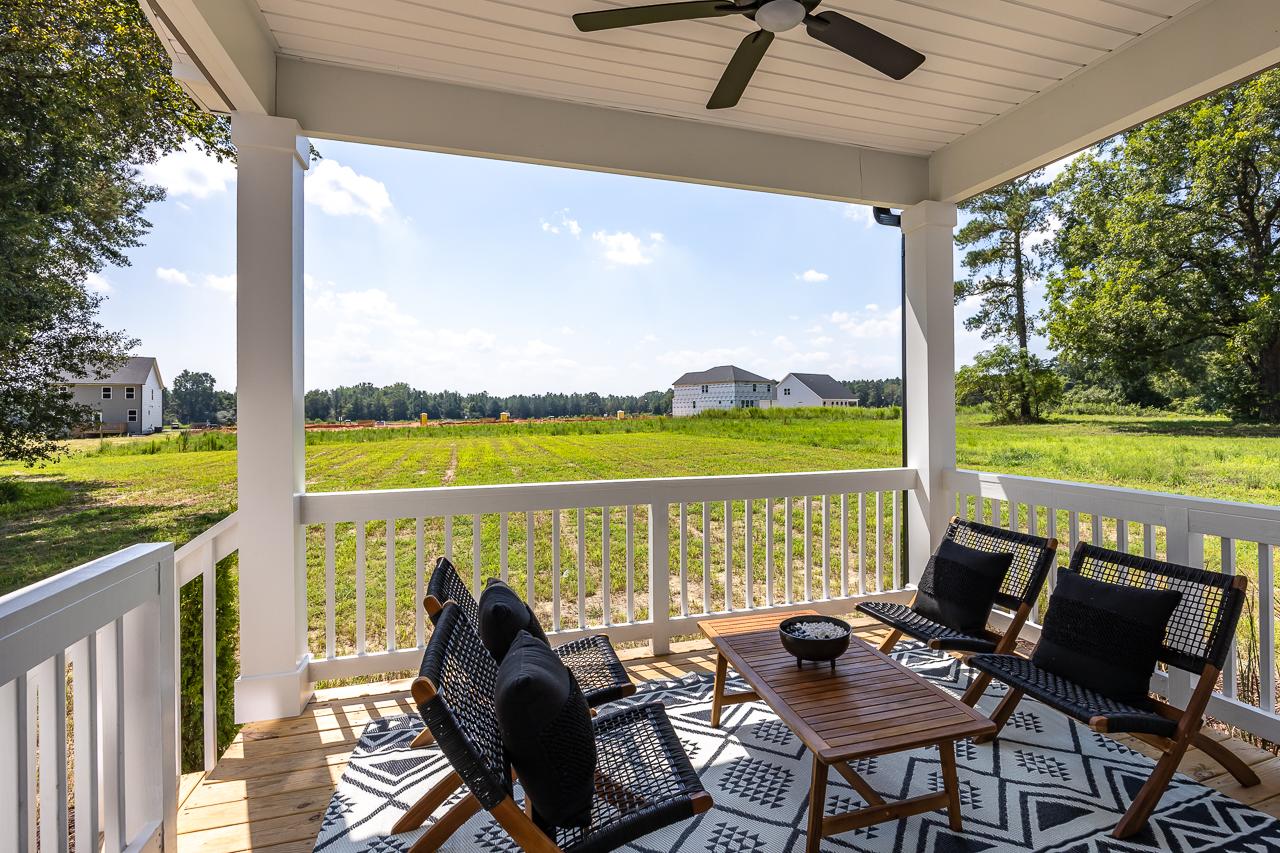 Covered deck with ceiling fan and outdoor seating overlooking green fields and farmhouse homes at Wellers Knoll in Lillington NC