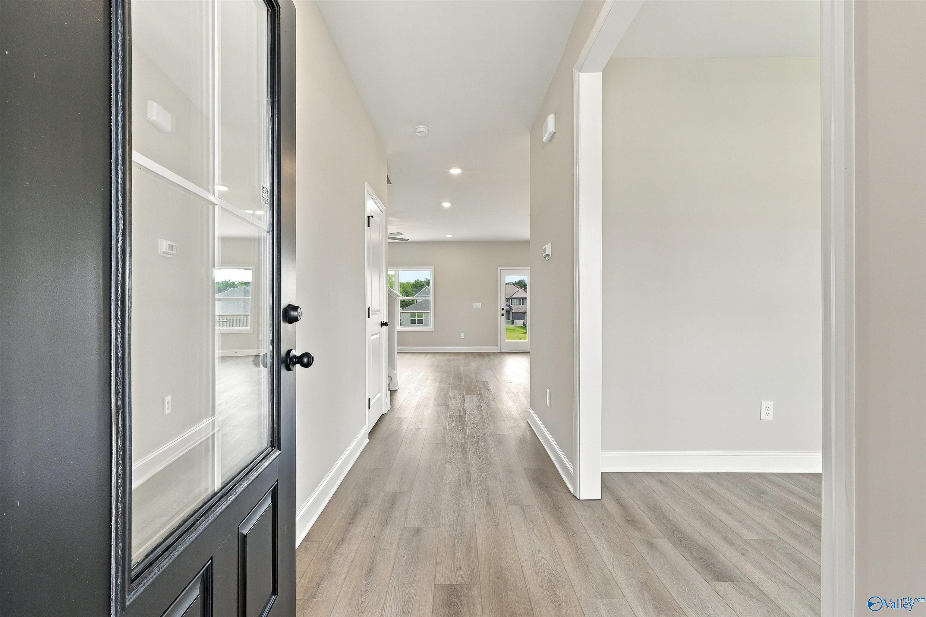 Foyer with black glass-panel front door and luxury vinyl plank flooring in Davidson Homes The Shelby A, The Meadows, Athens AL