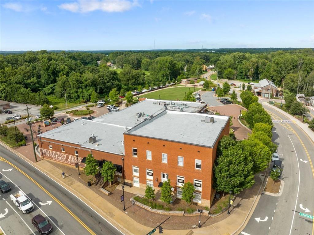 Aerial view of red brick Presbyterian building with flat roof, surrounded by lush trees, parking areas, and roads in Wehunt Meadows, Hoschton, Georgia