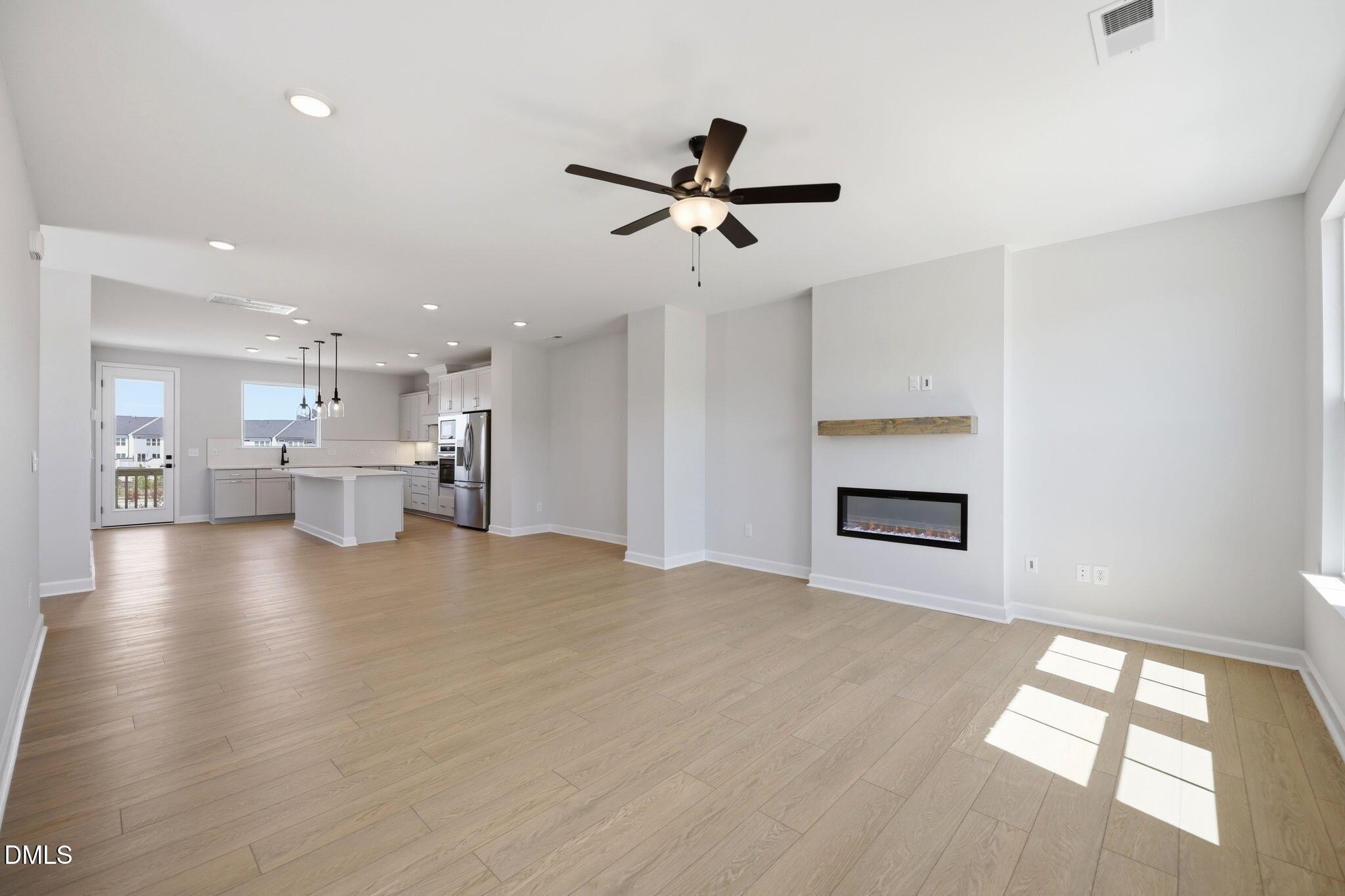 Open-concept living room with modern fireplace and kitchen in The Avery floor plan at Forestville Yard, Knightdale, NC.
