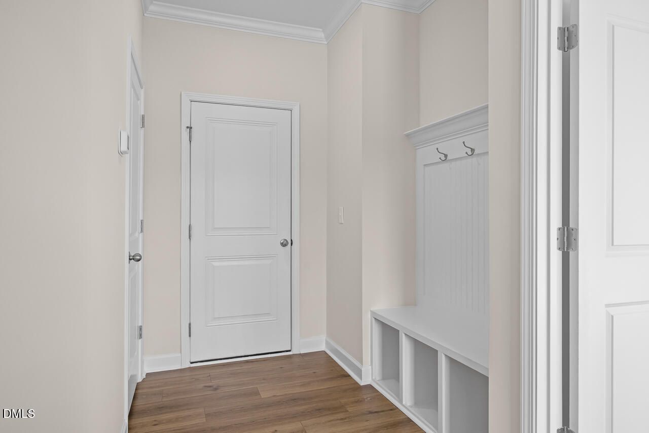 Bright mudroom entry with built-in bench, coat hooks, and wood-look flooring in Davidson Homes The Mitchell plan, Knightdale NC