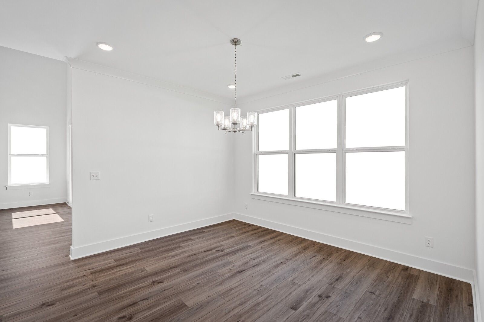 Bright dining room with hardwood floors, modern chandelier, and large windows in Davidson Homes The Hawkins, Murfreesboro, TN