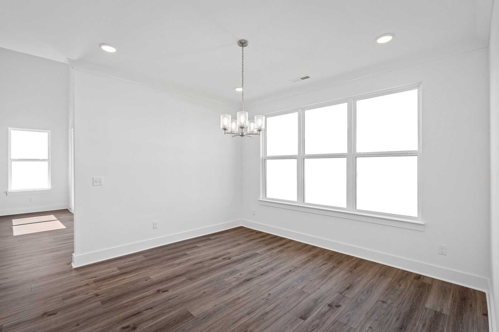 Bright dining room with hardwood floors, modern chandelier, and large windows in Davidson Homes The Hawkins, Murfreesboro, TN