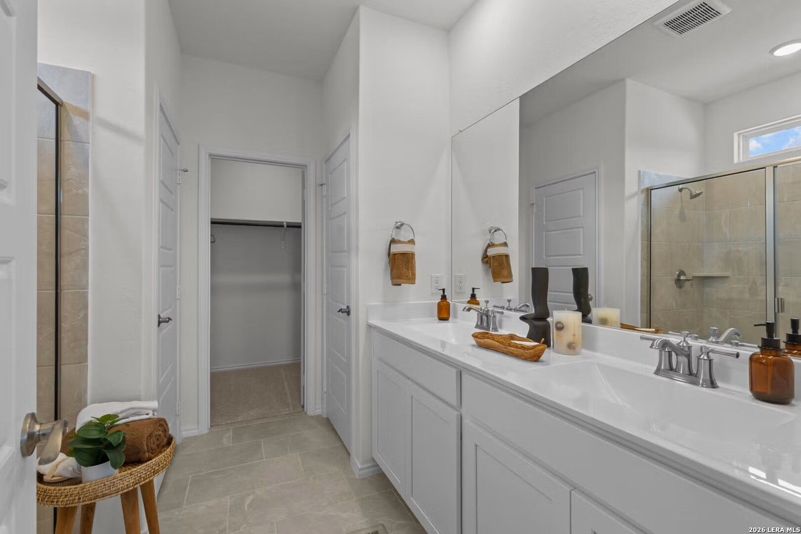 Modern master bathroom with white double vanity, glass shower, walk-in closet in Davidson Homes The Daphne K, San Antonio
