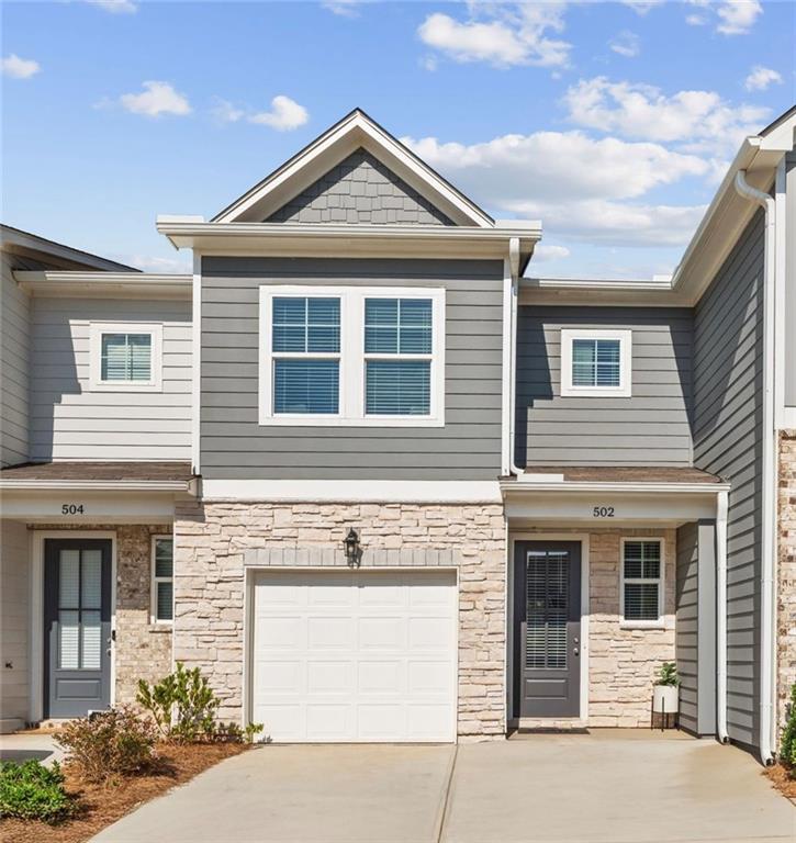 Contemporary 2-story Durant A townhome exterior with gray siding, stone accents, and 1-car garage in Stegall Village, Emerson, GA