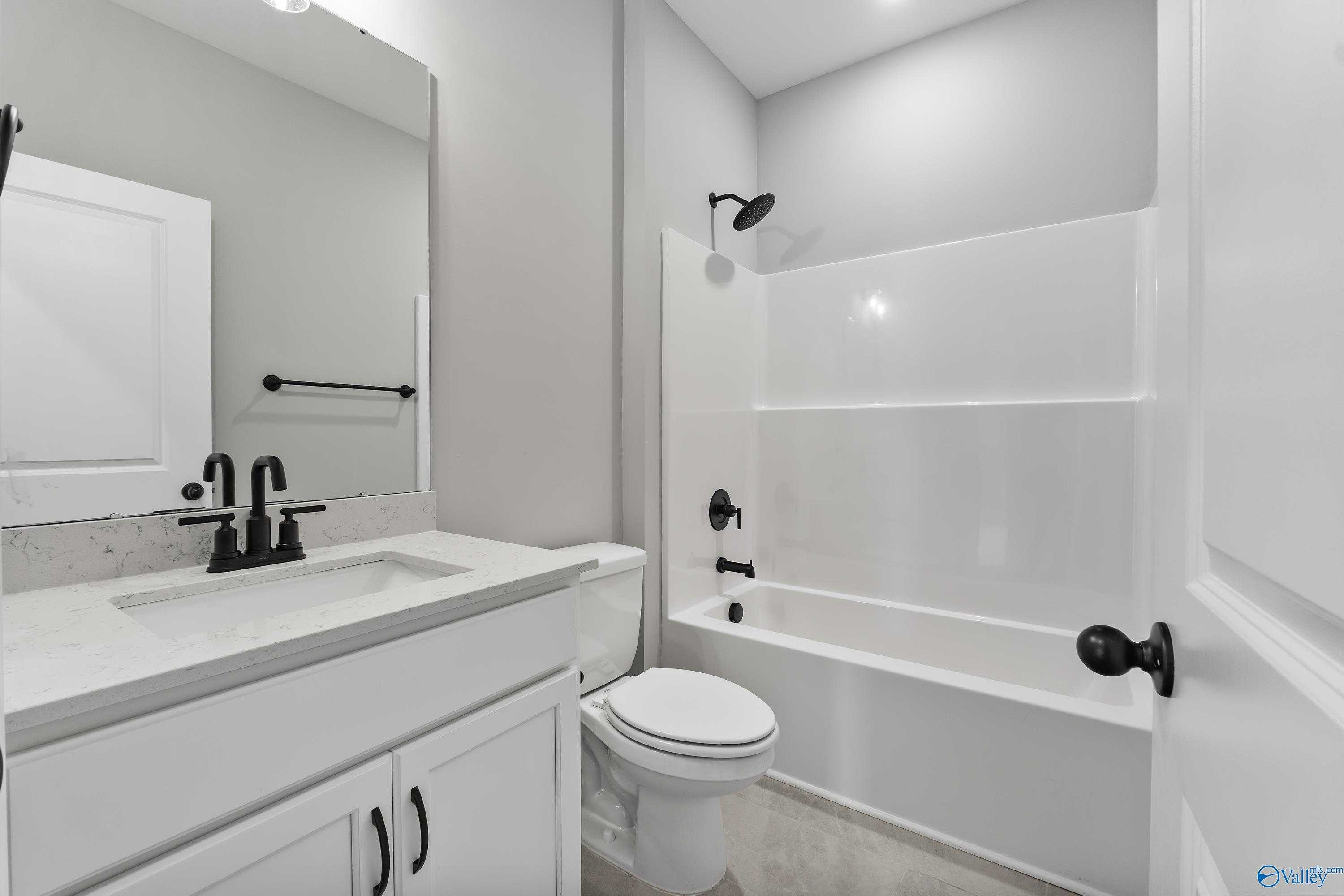 Elegant full bathroom with white vanity, quartz countertop, tub, and glass shower in Davidson Homes The Montgomery B With Bonus, Toney, AL