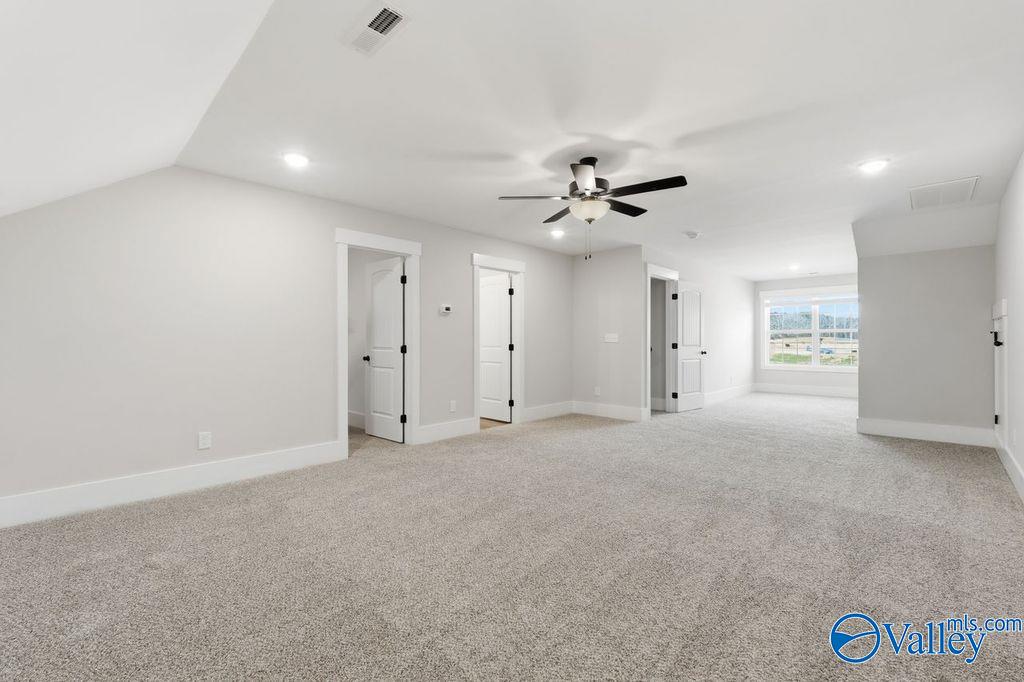 Spacious upstairs bonus room with vaulted ceiling, ceiling fan, and carpet flooring in Davidson Homes The Rockford, Hartselle, Alabama